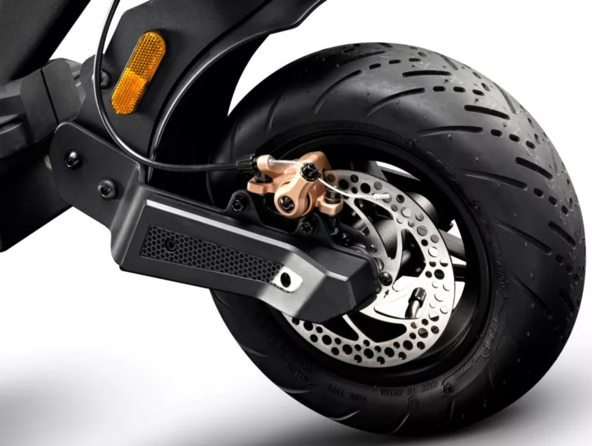 Gros plan sur la roue arrière d'une trottinette électrique, montrant le disque de frein et la suspension.