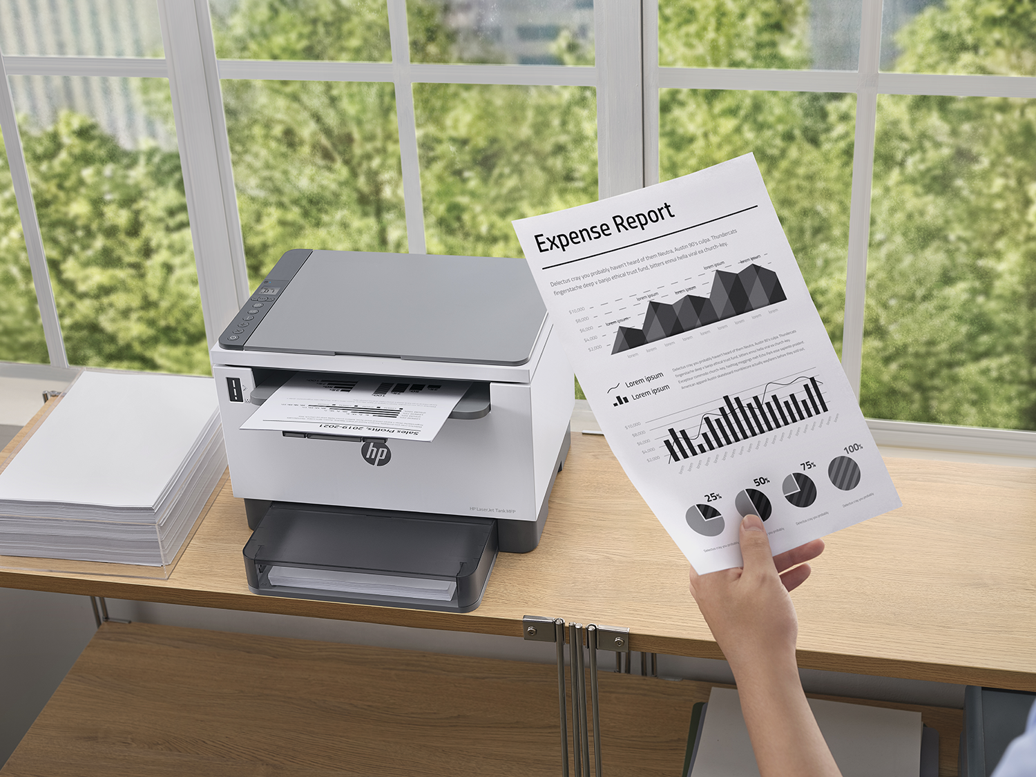 Printer printing an expense report.  A person is holding a printed graph.