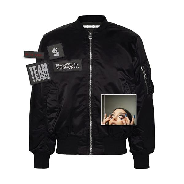 Schwarze Bomberjacke mit Aufnähern. Ein Foto von Augen ist auch auf der Jacke.