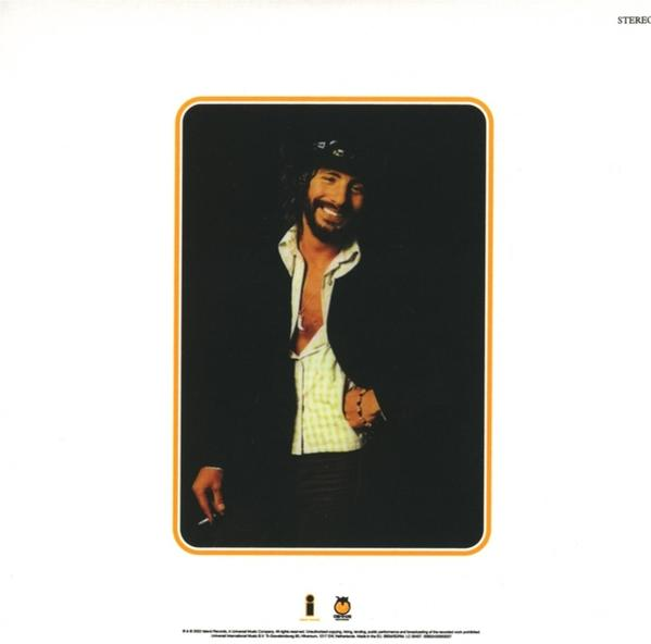 Bruce Springsteen lächelt in Jacke, offenem Hemd und Bandana. Hält eine Zigarette.