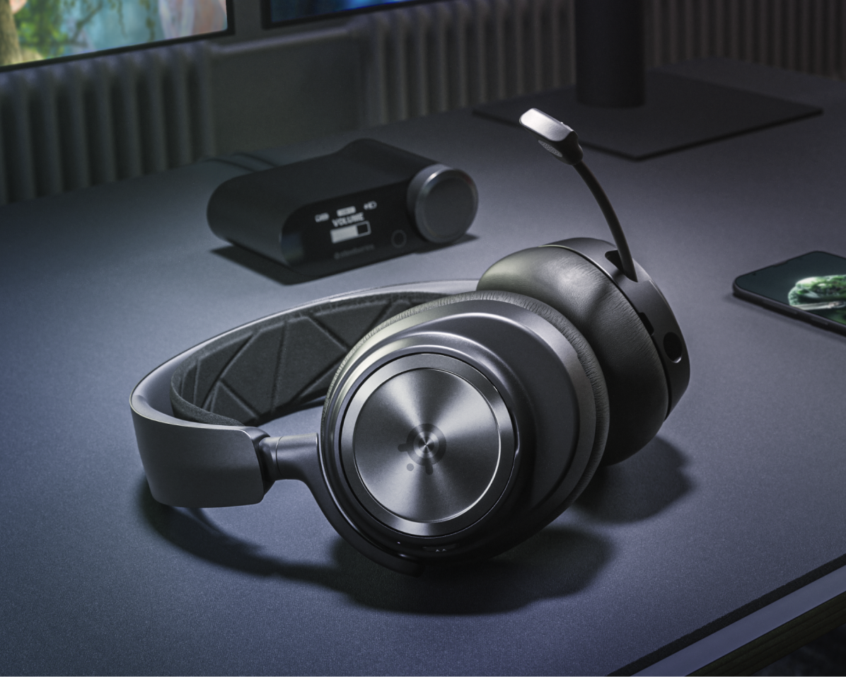 Schwarze Gaming-Kopfhörer auf einem Schreibtisch. Ein Soundmixer und ein Smartphone sind ebenfalls vorhanden.