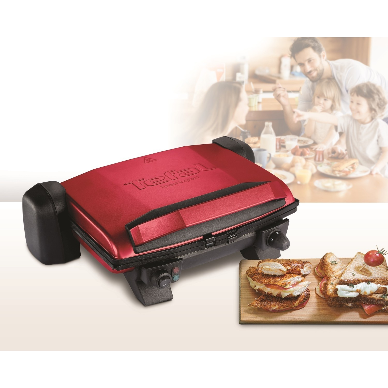Kırmızı bir Tefal Optigrill, sandviçler ve arka planda bir aile. Kırmızı ve siyah renk şeması.