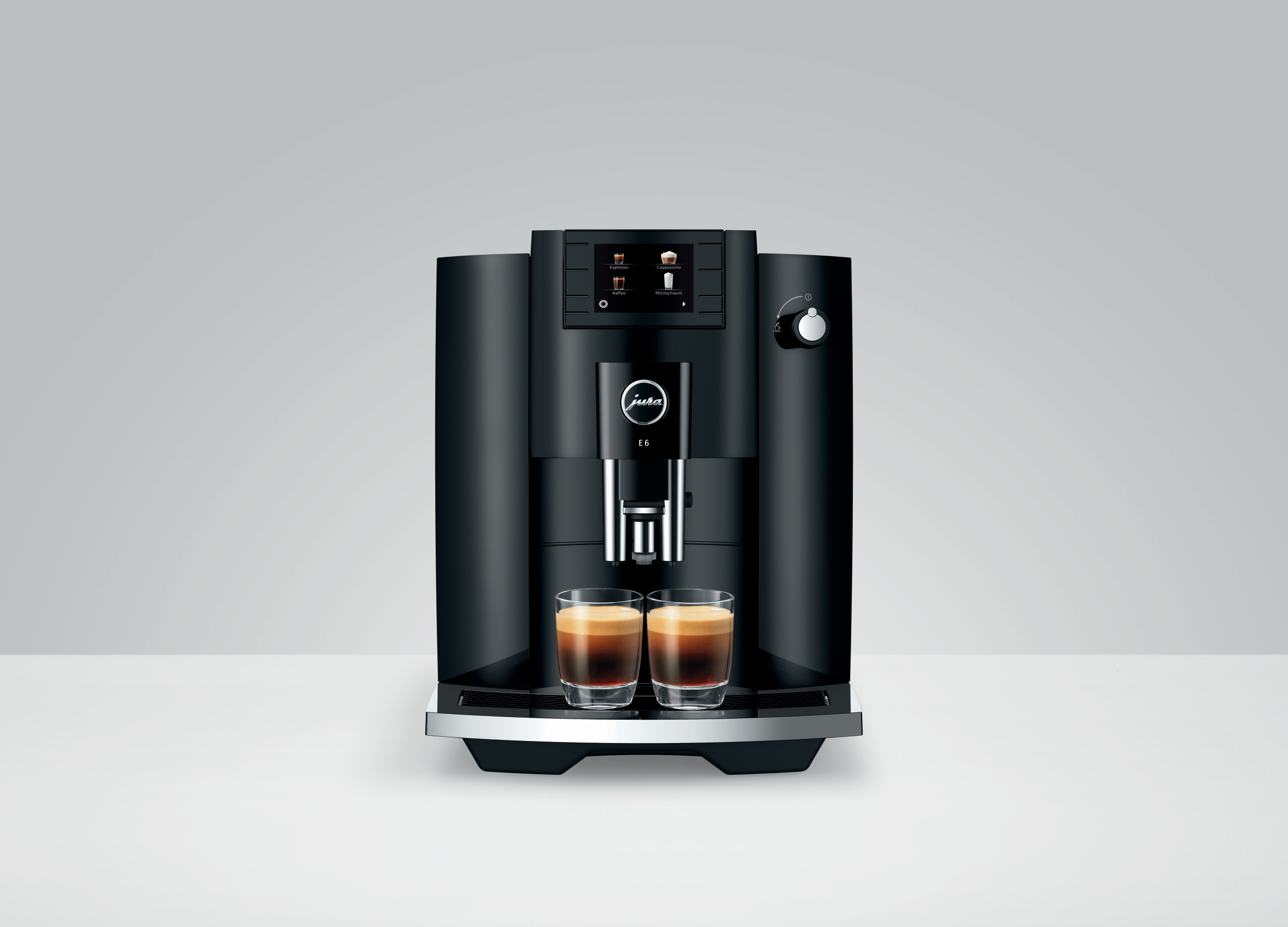 Schwarze Espressomaschine mit zwei Kaffeegläsern auf weißer Oberfläche.