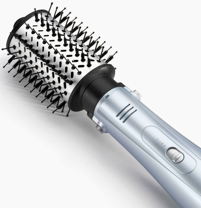 Gros plan d'une brosse à coiffer, manche bleu, poils blancs et noirs.