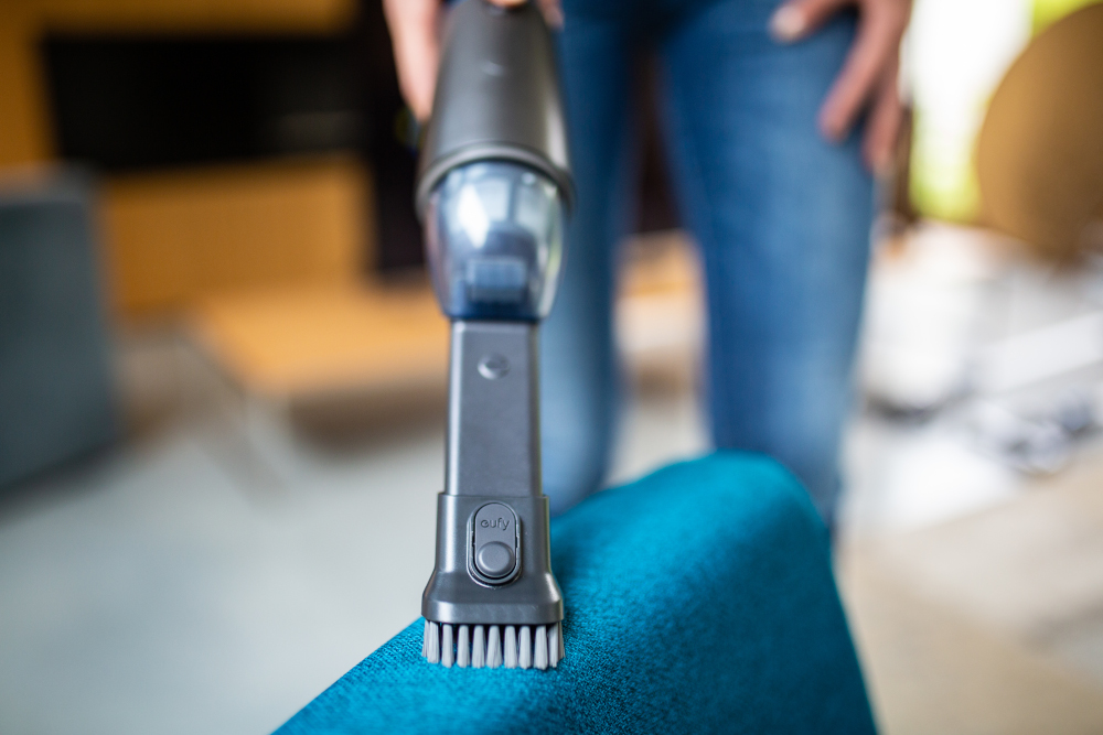 Gros plan de brosse d'aspirateur nettoyant une chaise bleue.