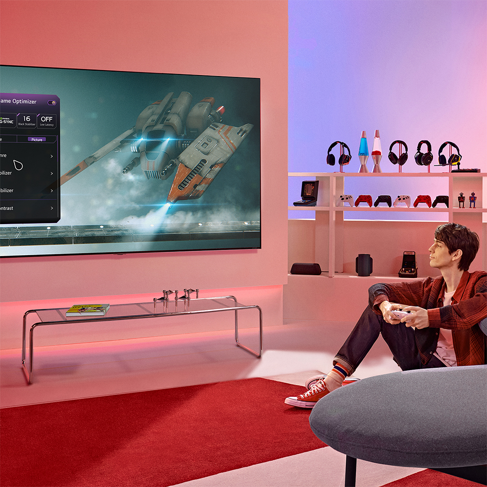 Önünde kırmızı halı bulunan, aksesuarlarla bir TV'de video oyunu oynayan kişi.