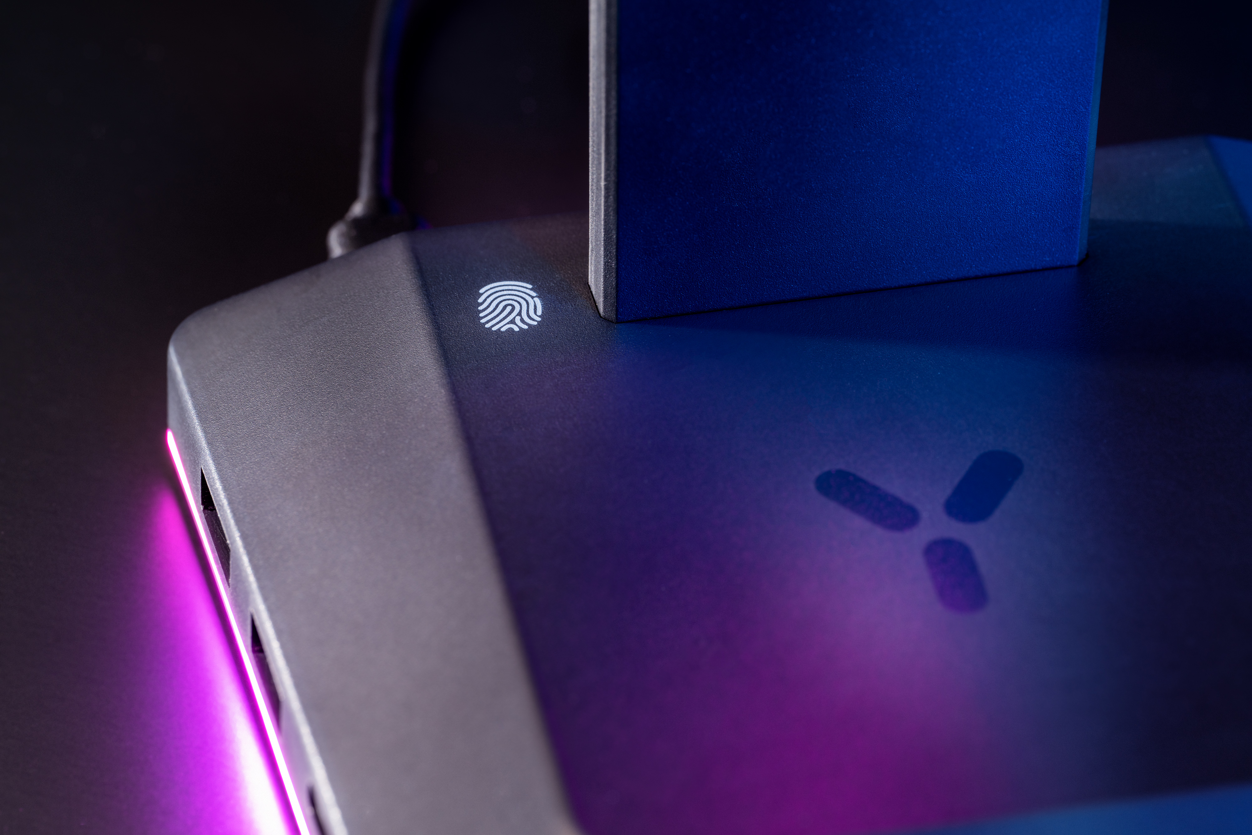Dunkelgraues Gerät mit Fingerabdrucksensor und Y-förmigem Logo auf dunklem Hintergrund.