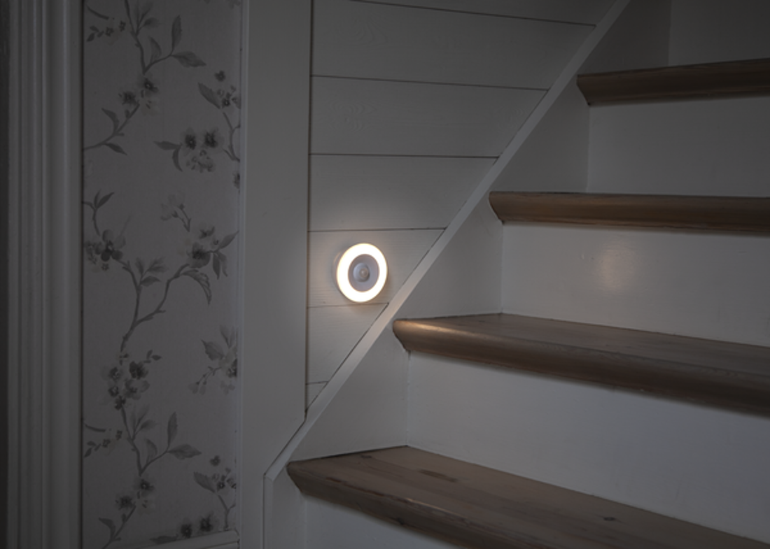 Scala con un apparecchio di illuminazione con sensore di movimento sulla parete laterale.