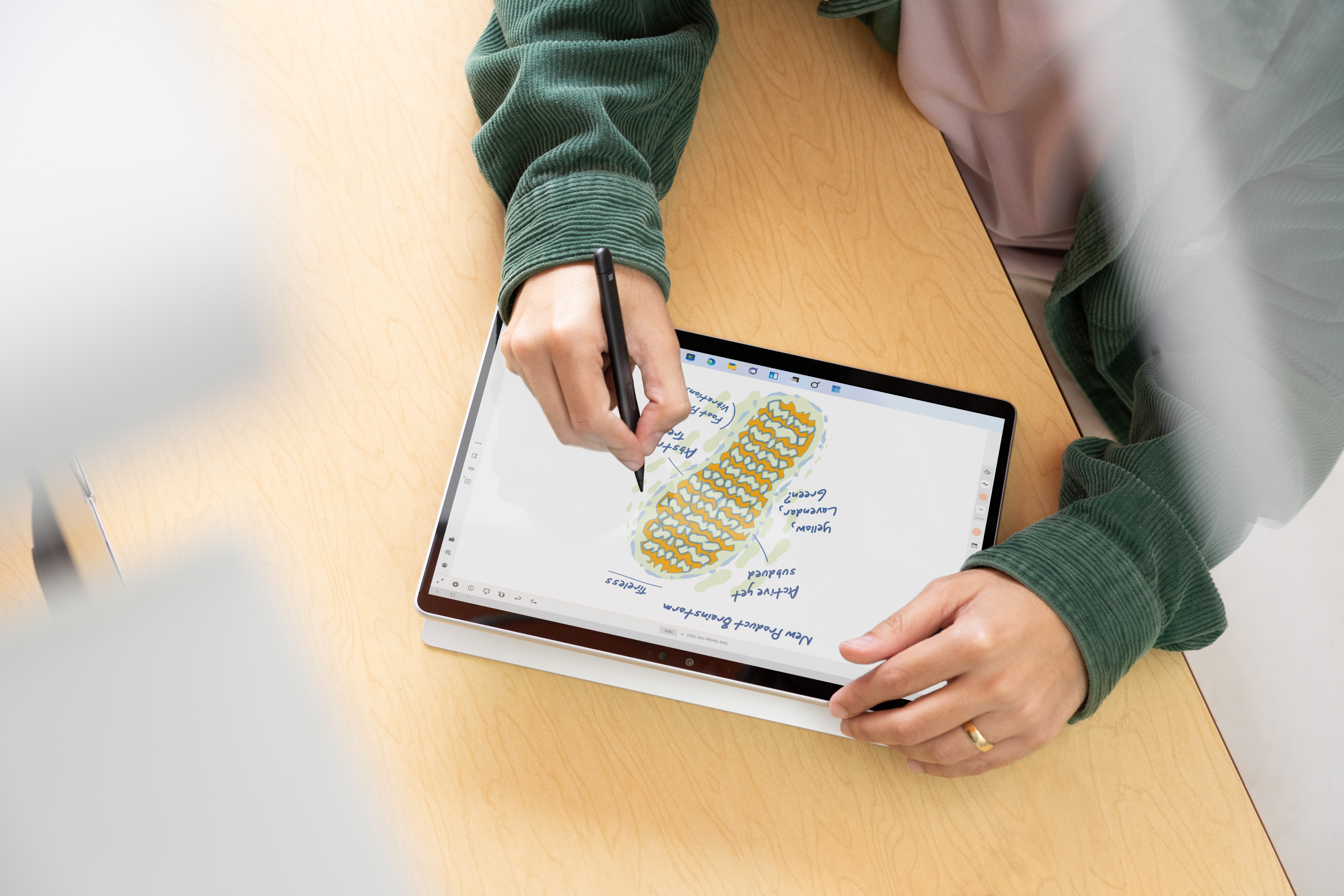 Handen die met een stylus op een tablet tekenen, met een diagram op het scherm.