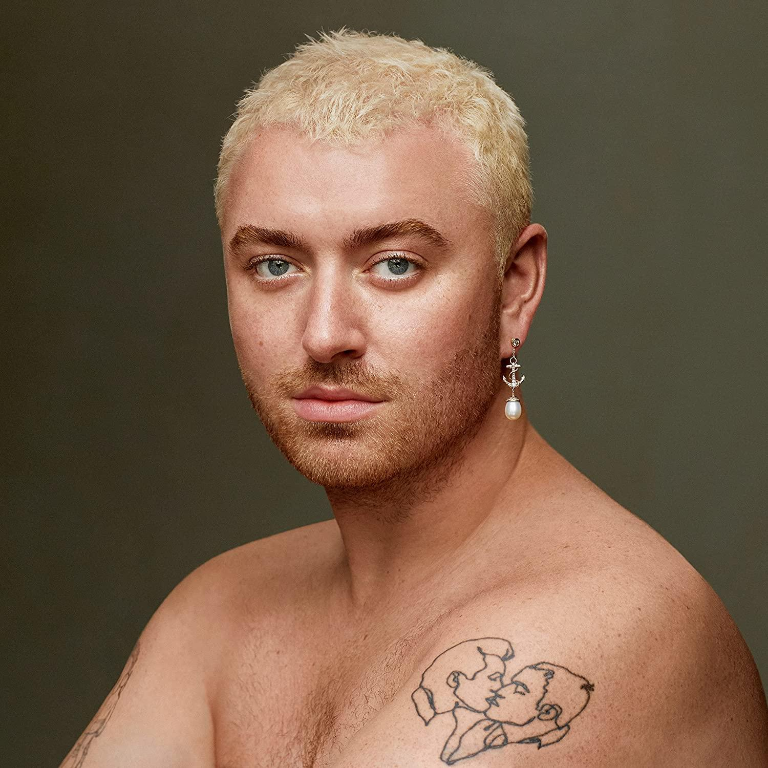 Porträt von Sam Smith, blondes Haar, Ohrring, Tattoo auf der Brust, Blick in die Kamera.