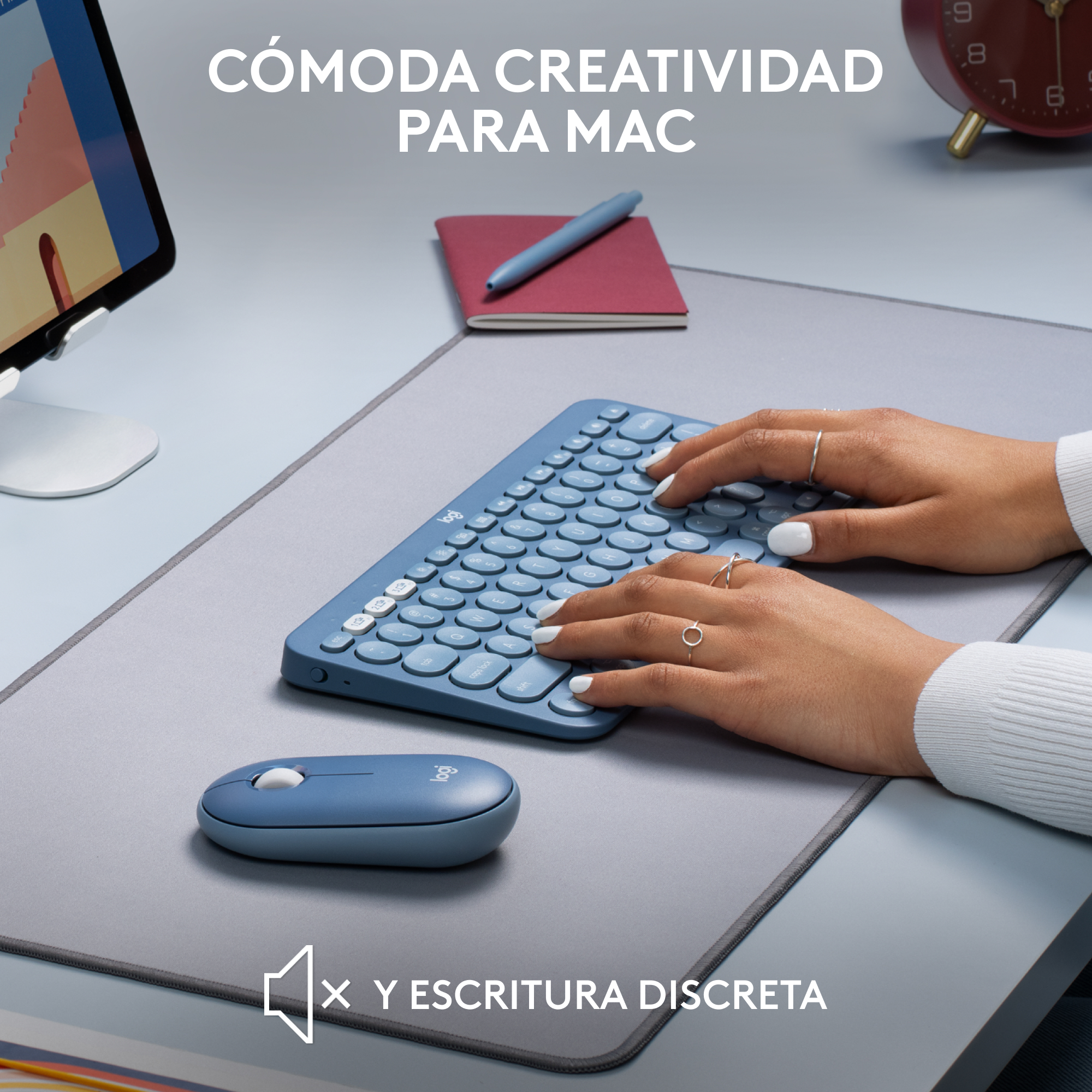 Manos en un teclado y ratón azules. Alfombrilla gris en un escritorio gris.