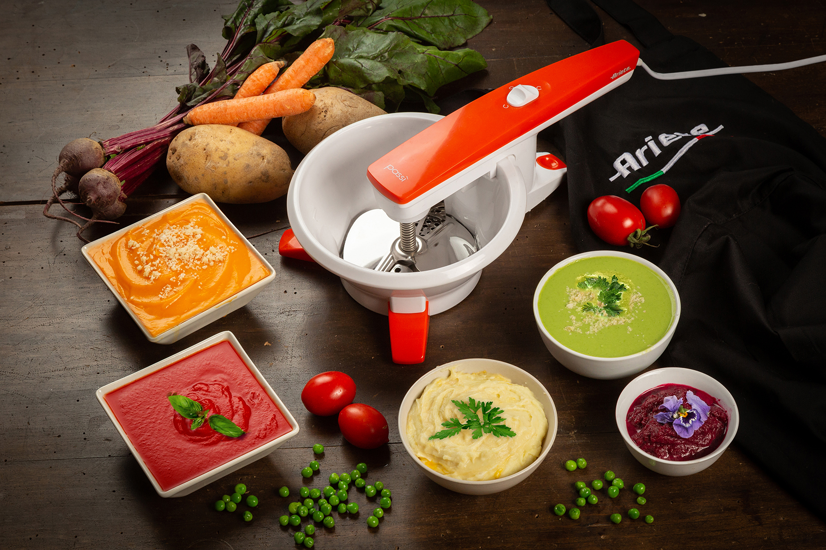 Un procesador de alimentos con verduras y sopas en cuencos. Zanahorias, remolachas, patatas y tomates son visibles.