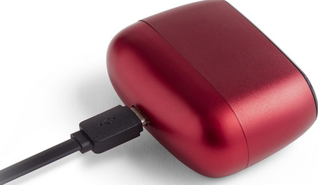 Un dispositivo rosso a forma ovale con una porta USB e un cavo di ricarica nero collegato.