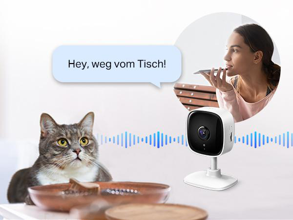 Frau spricht mit einer Smart-Home-Kamera.