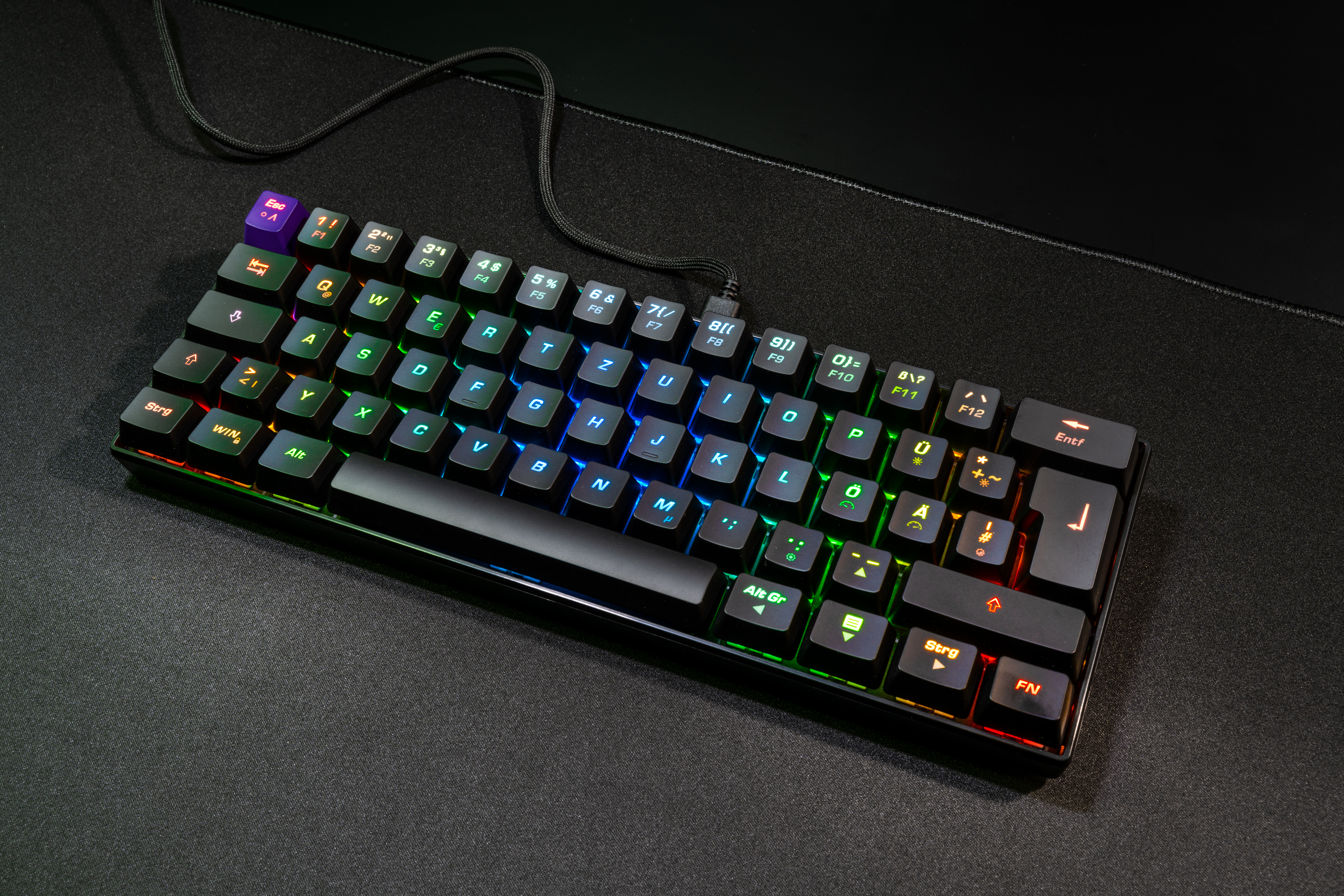 Schwarze Tastatur mit mehrfarbigen Tasten. Schwarze Oberfläche. Tasten sind in verschiedenen Farben beleuchtet.