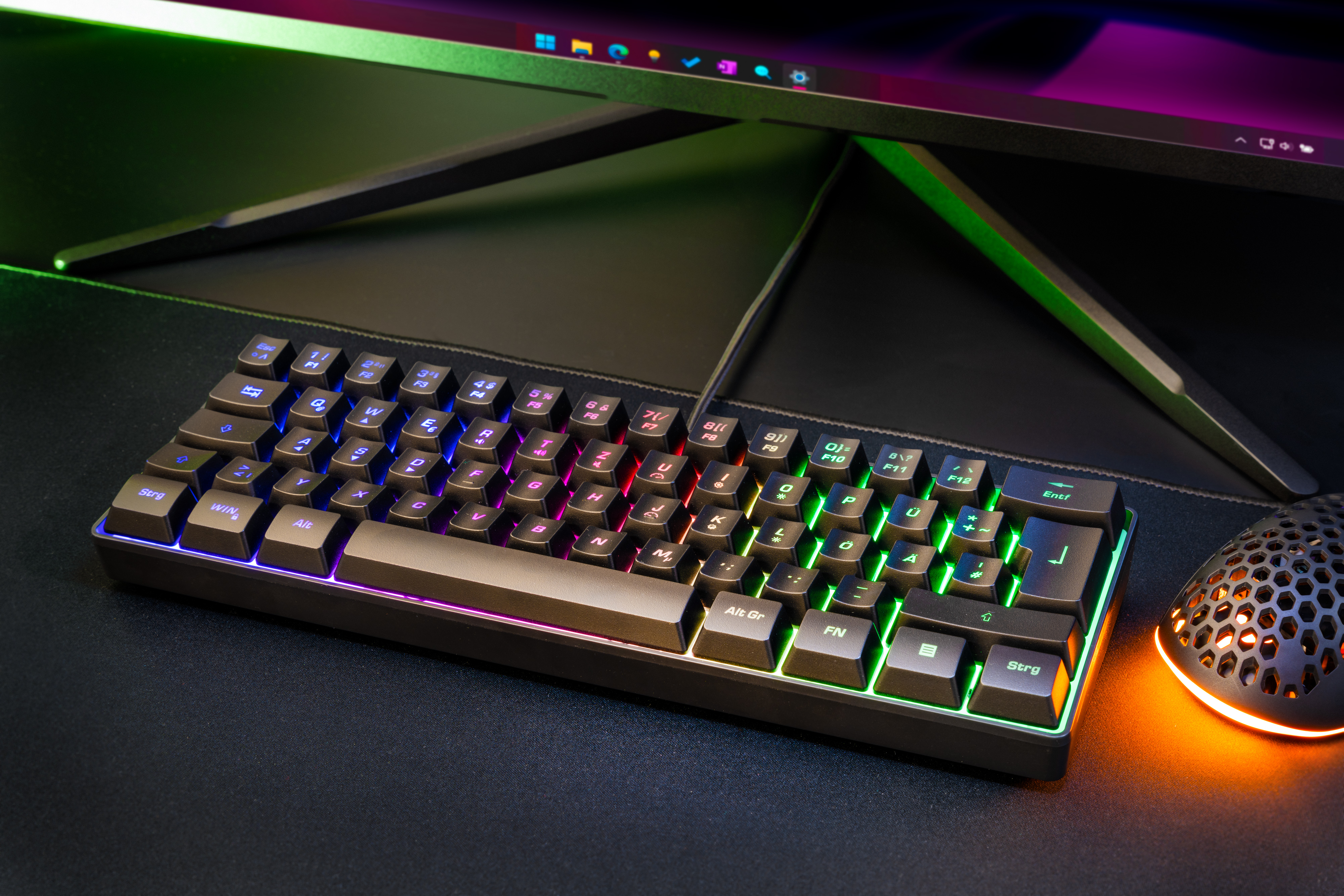 Eine Gaming-Tastatur mit beleuchteten Tasten und eine Maus auf schwarzer Oberfläche. Die Tastatur hat farbige Lichter.