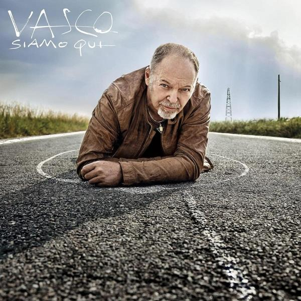 Homme sur la route, avec le texte 'VASCO'. Ciel nuageux et champs en arrière-plan.