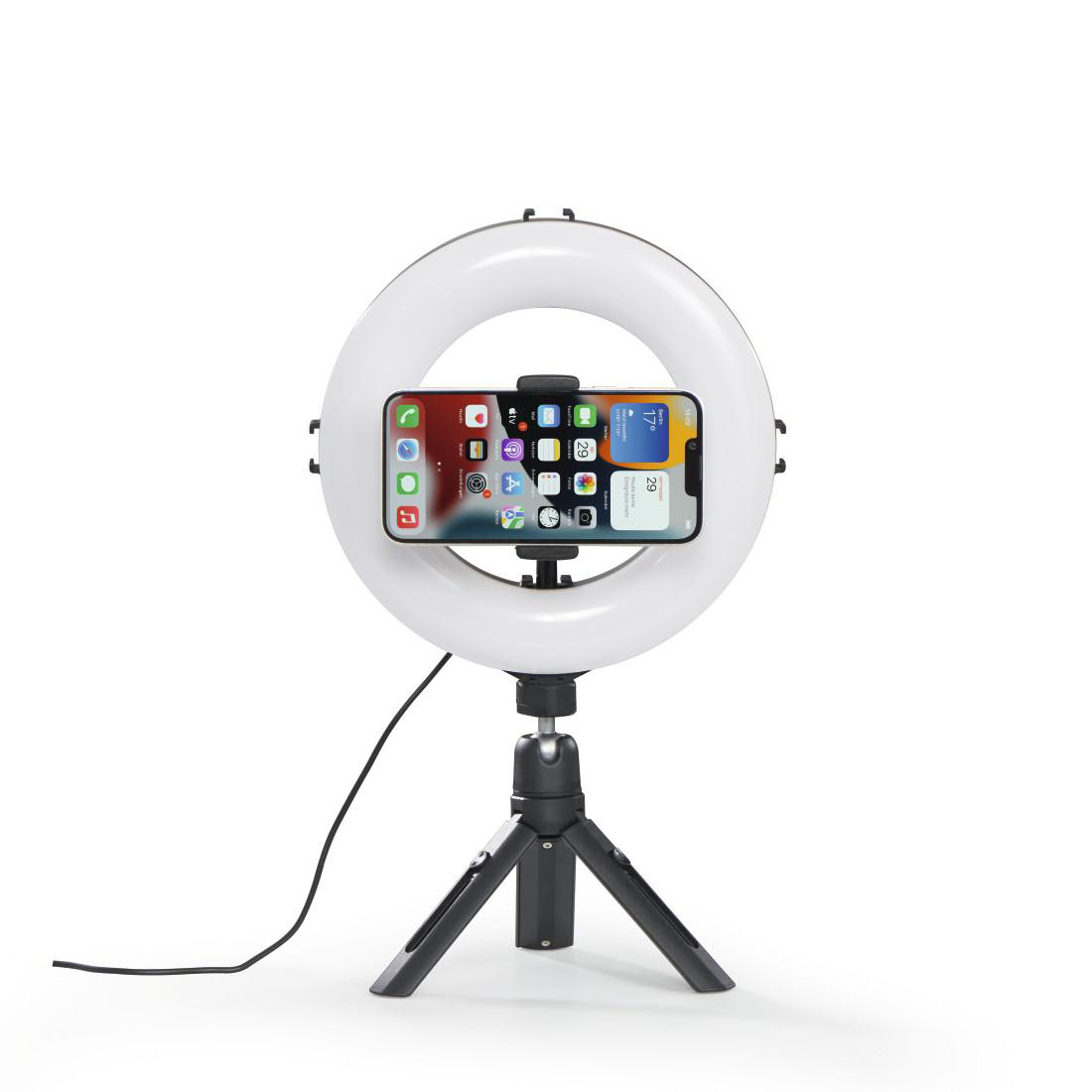 Ein Smartphone ist auf einem Ringlicht auf einem Stativ montiert, weißer Hintergrund.