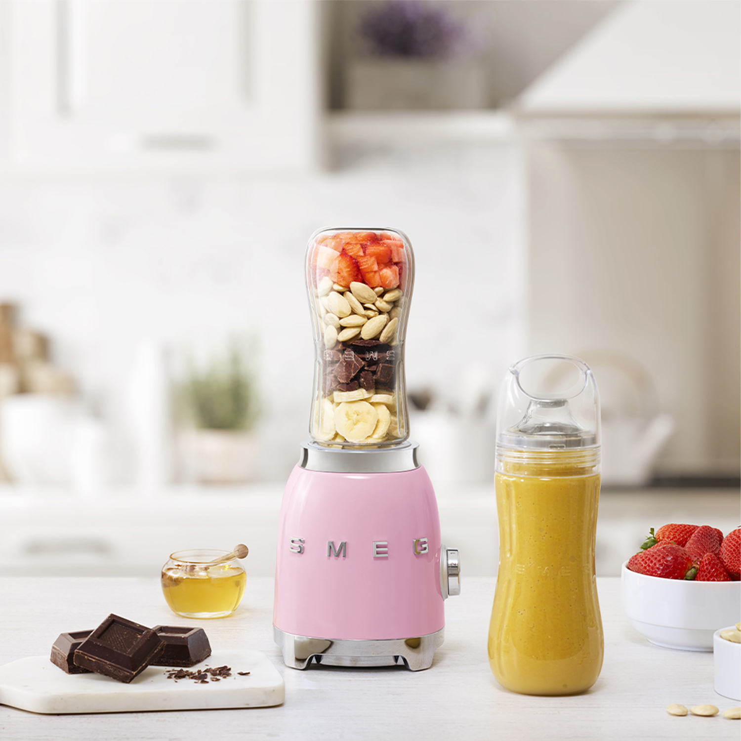 Frullatore SMEG rosa con ingredienti nel barattolo, e barattolo di miele.