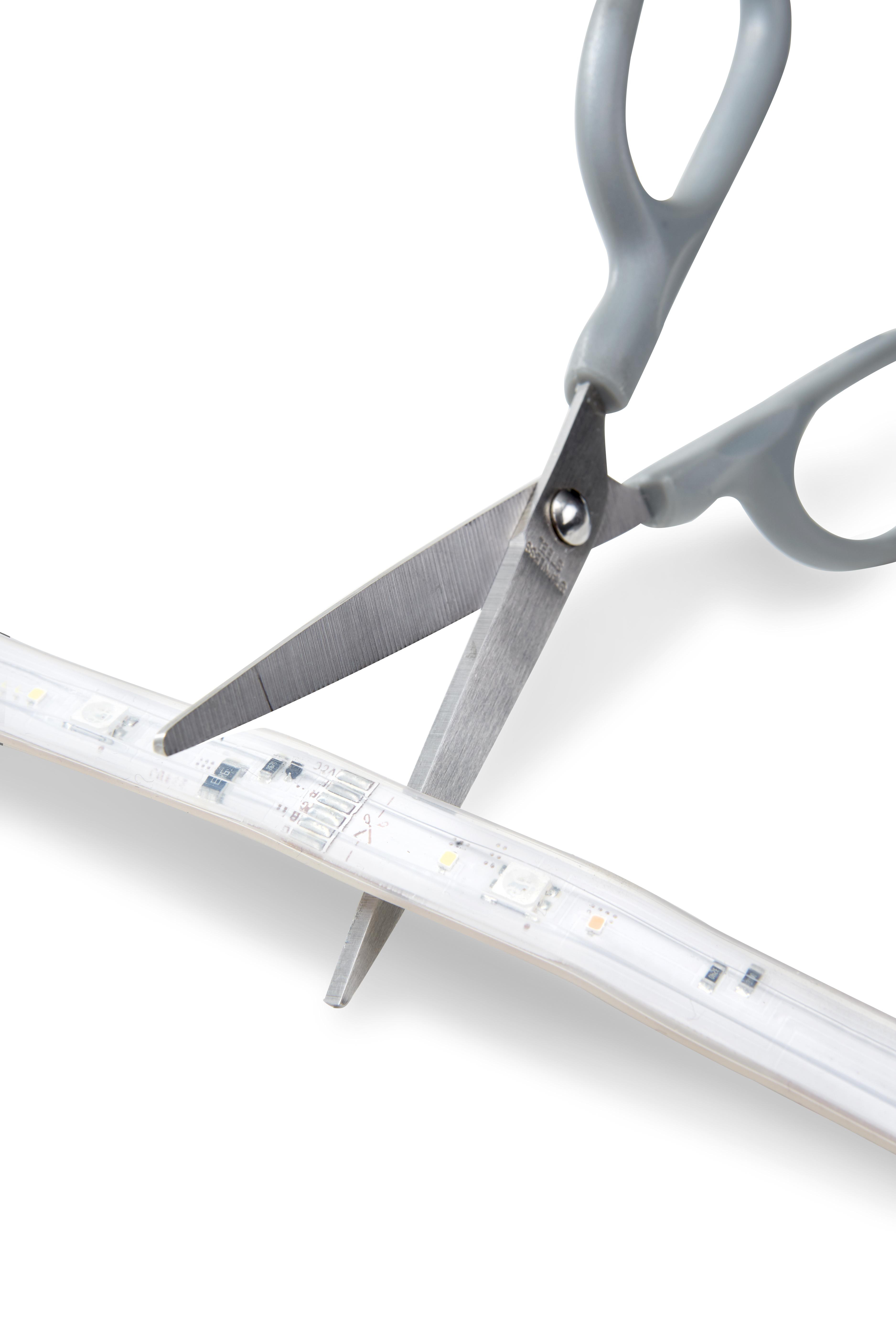Schere schneidet ein LED-Streifenlicht. Graue Schere auf weißem Hintergrund.
