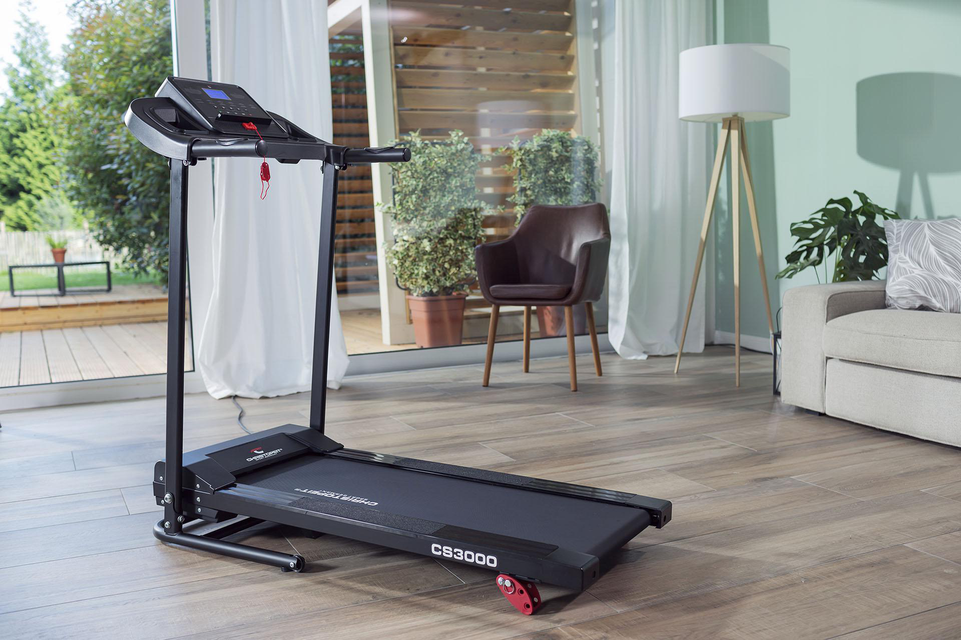 Laufband in einem hellen Wohnzimmer mit Lampe und Couch.