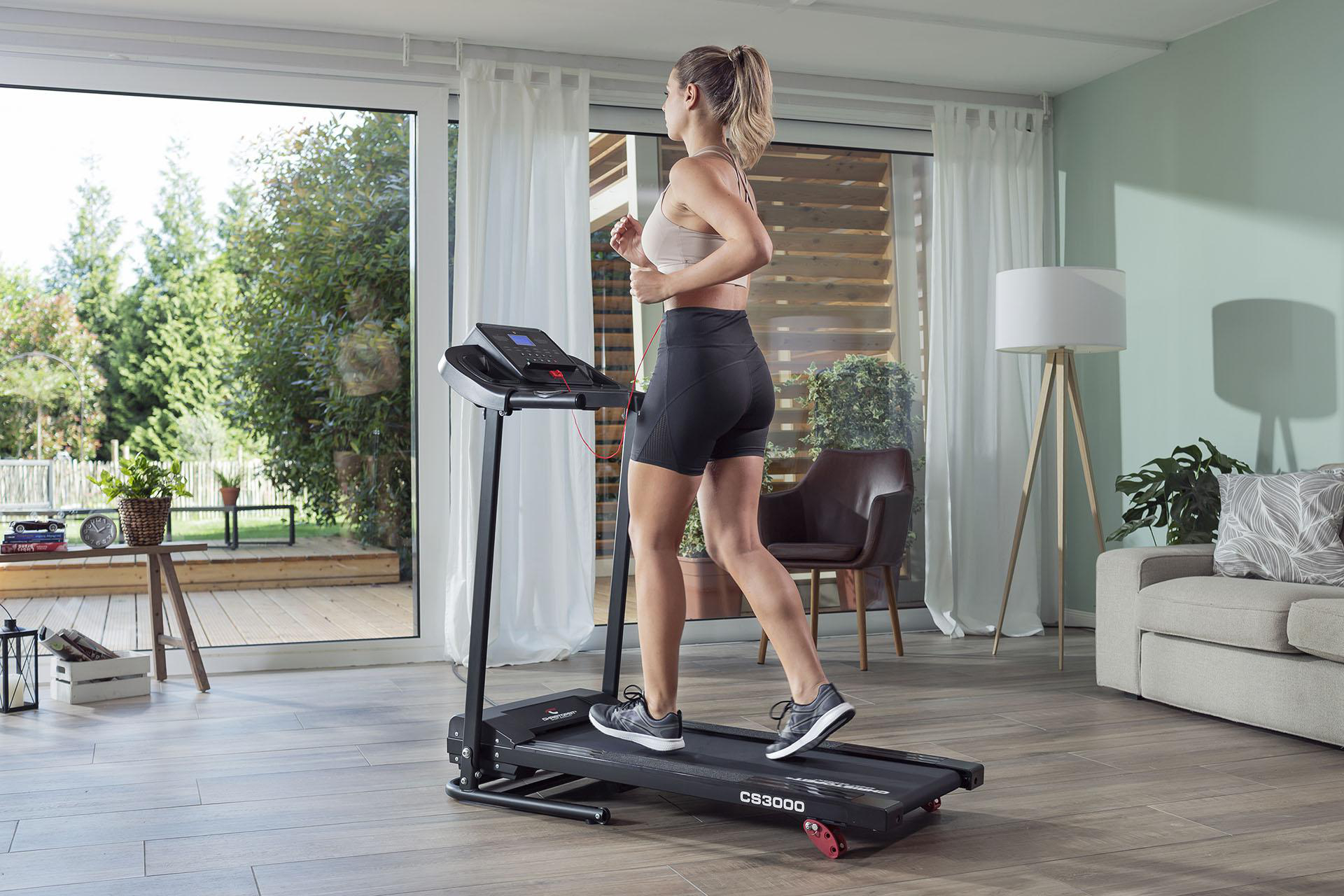 Eine Frau, die in einem Home Gym auf einem Laufband läuft.