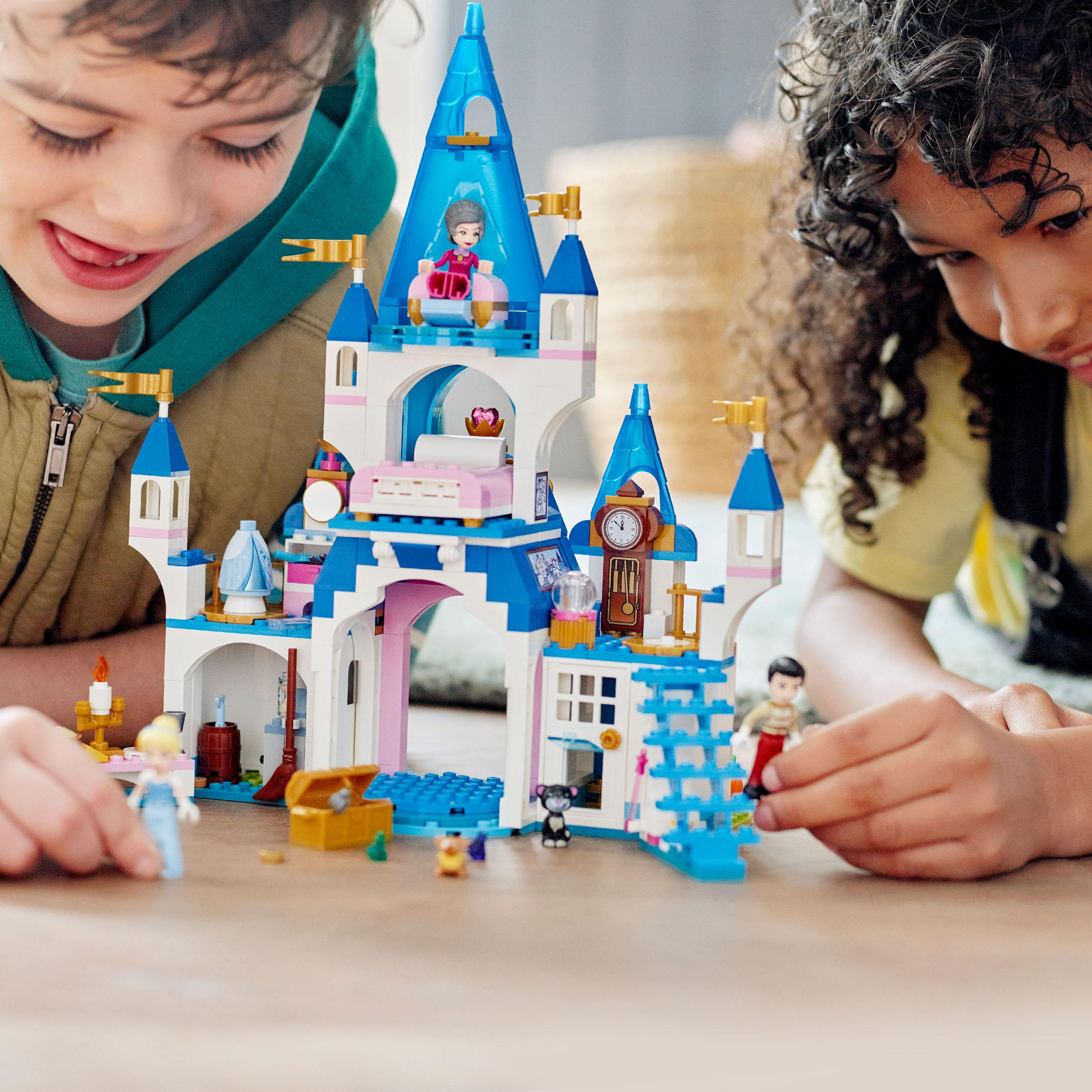 Zwei Kinder spielen mit einer Lego-Burg. Die Burg ist blau und weiß, mit Figuren und Zubehör.
