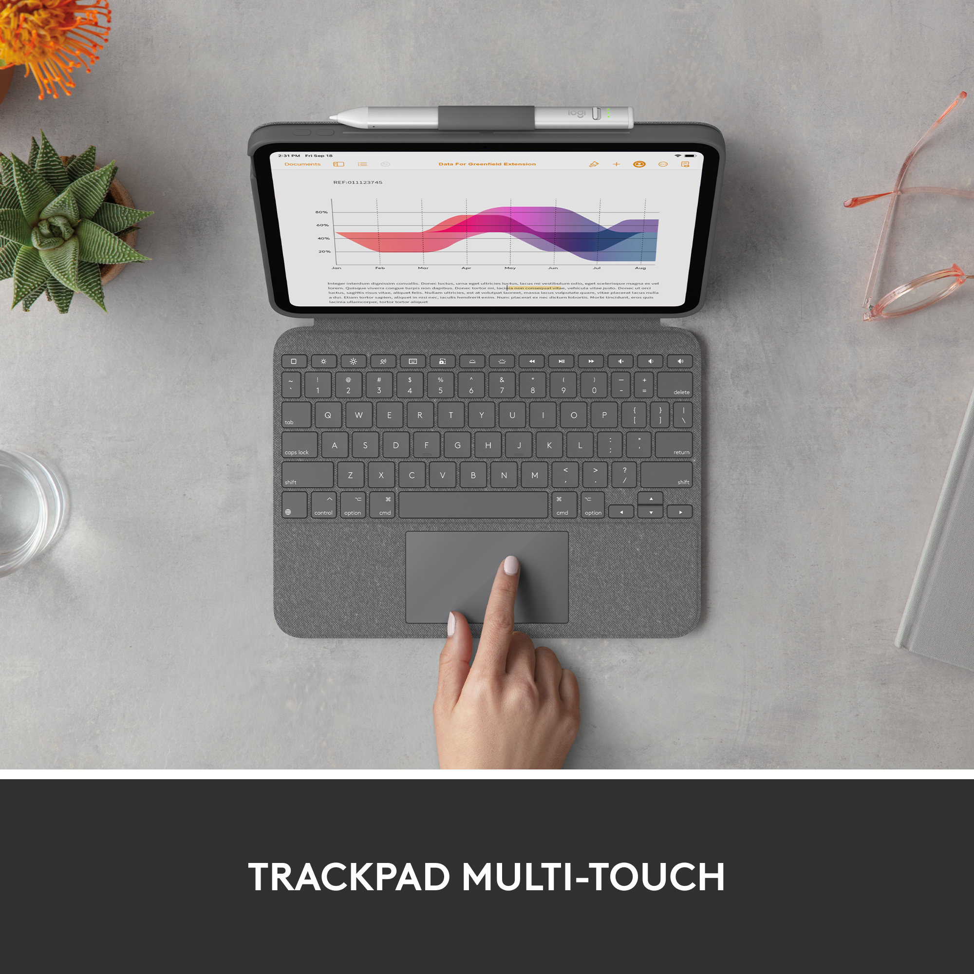 Tableta con teclado y lápiz. Una mano toca la pantalla. Superficie gris con una planta.