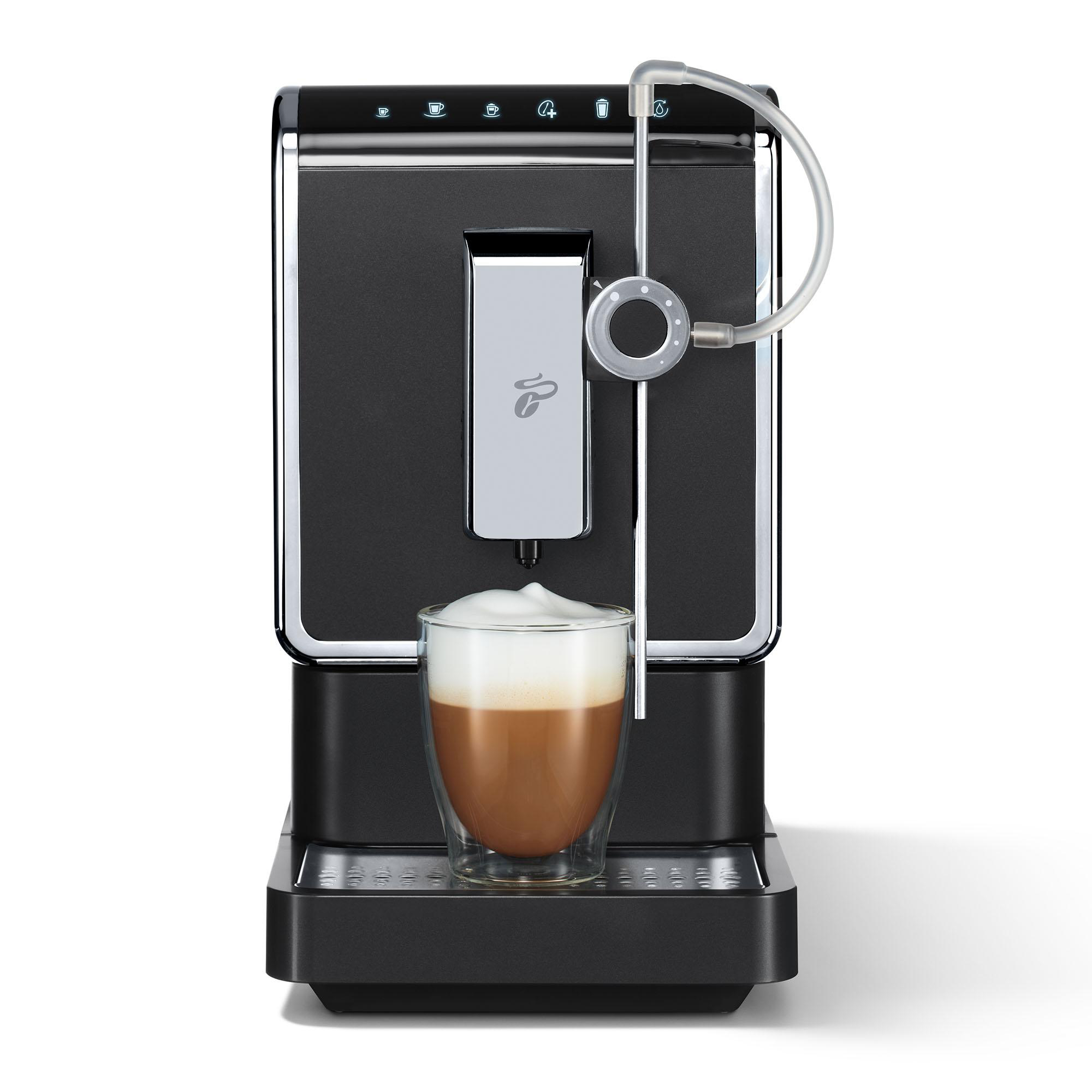 Eine schwarze Kaffeemaschine, die einen Cappuccino in eine Glastasse ausgibt.