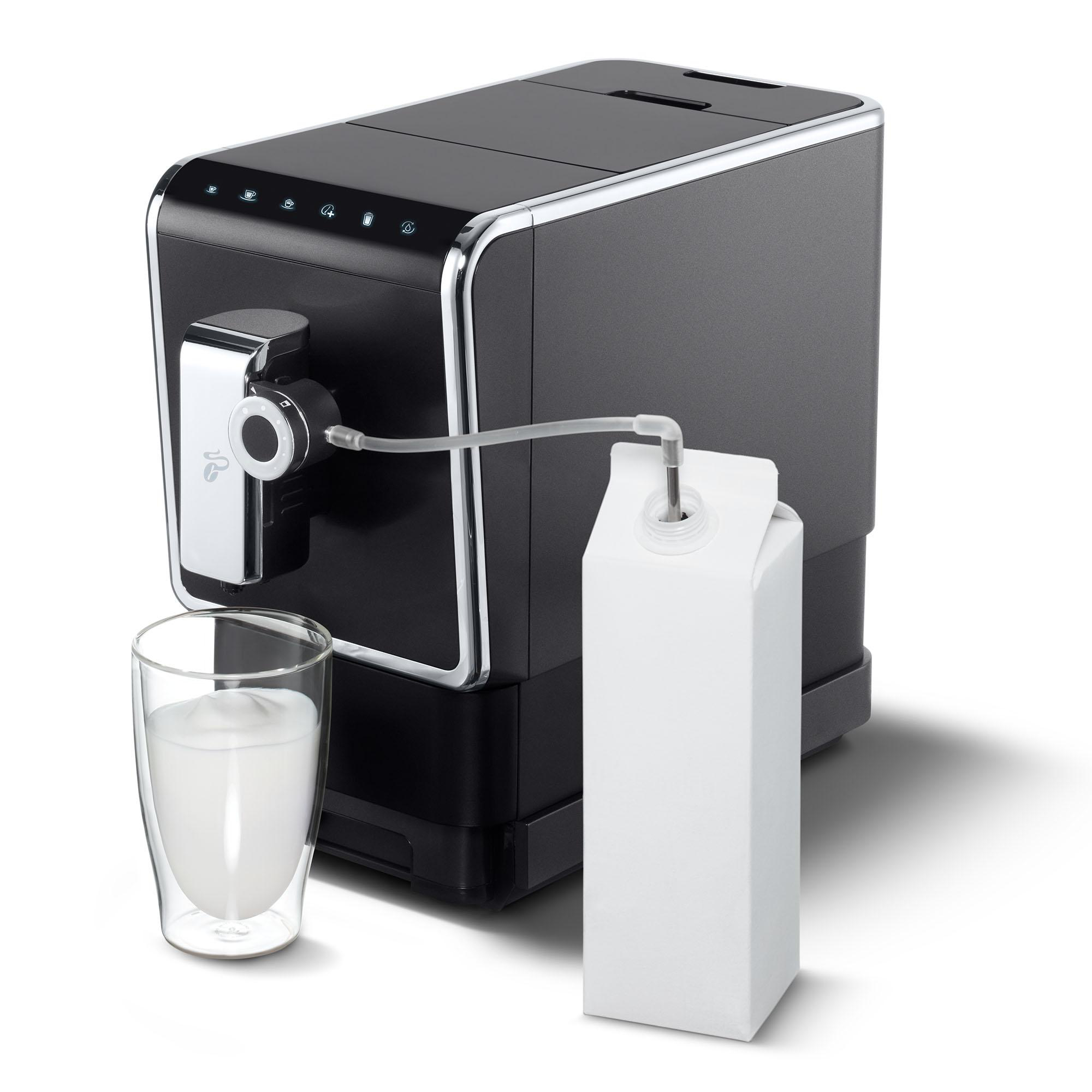 Schwarze Kaffeemaschine, die Milch in ein Glas und einen Karton abgibt. Weißer Hintergrund.