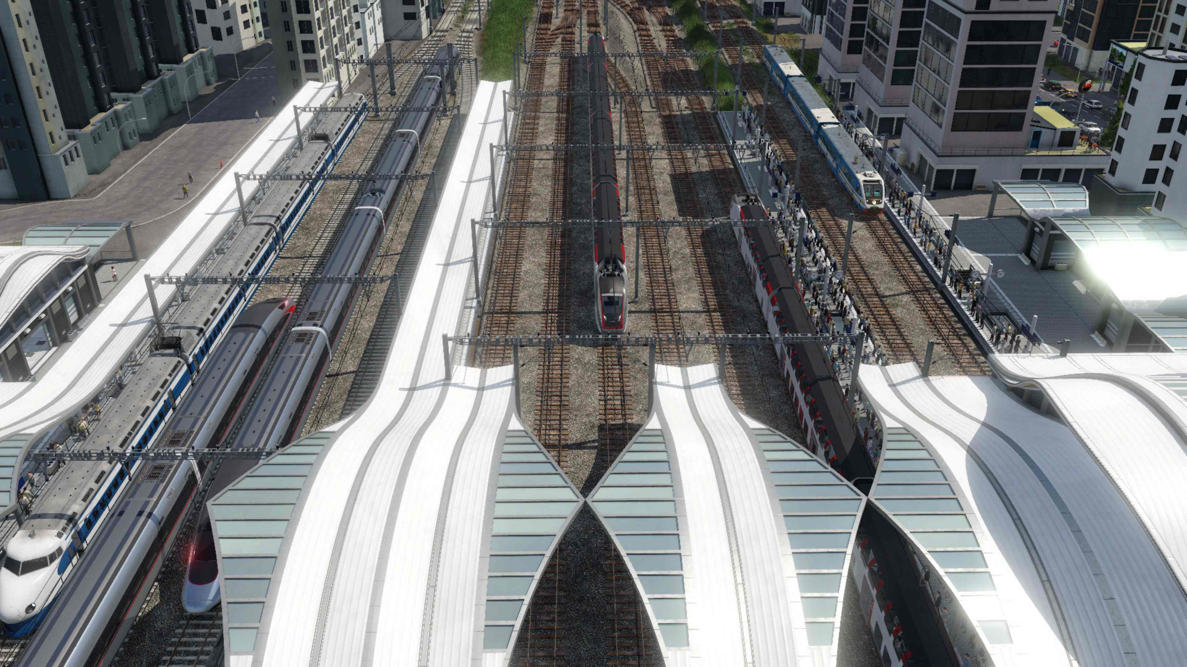 Vogelperspektive eines Bahnhofs mit mehreren Gleisen und Zügen, moderne Architektur.