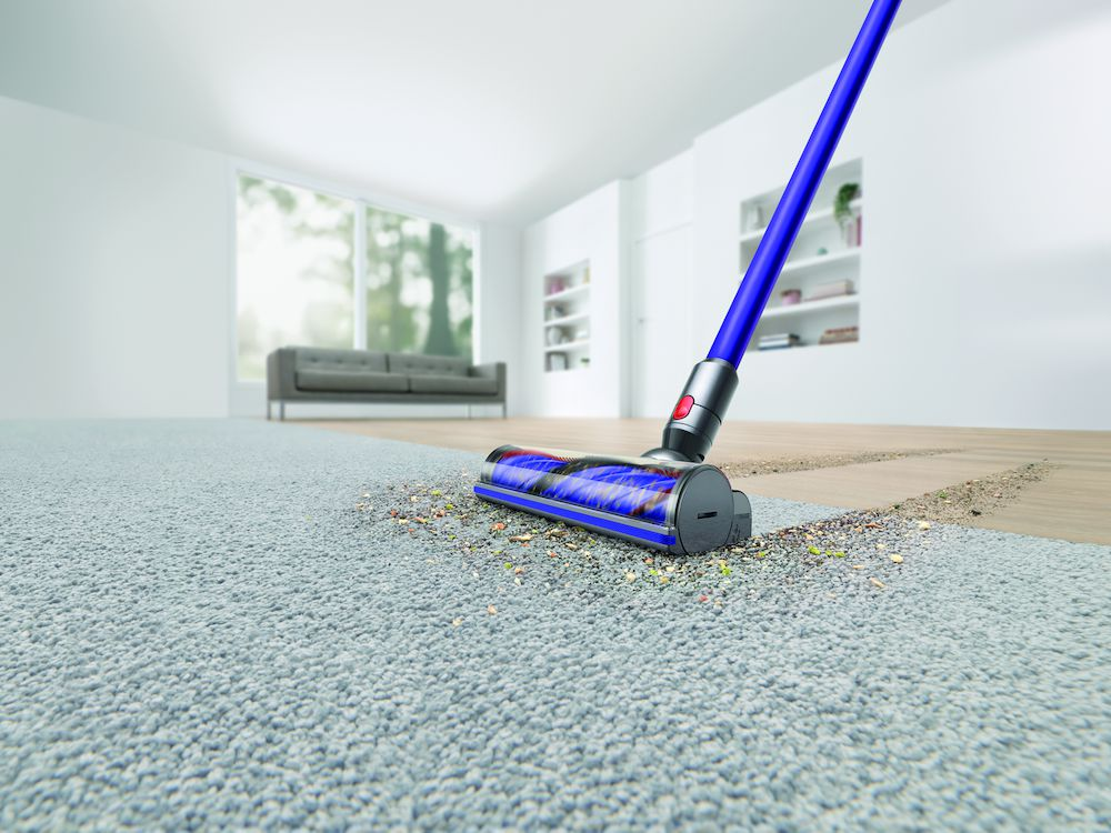 A vacuum cleaner cleaning a light gray carpet. Debris is visible on the carpet where it was cleaned.