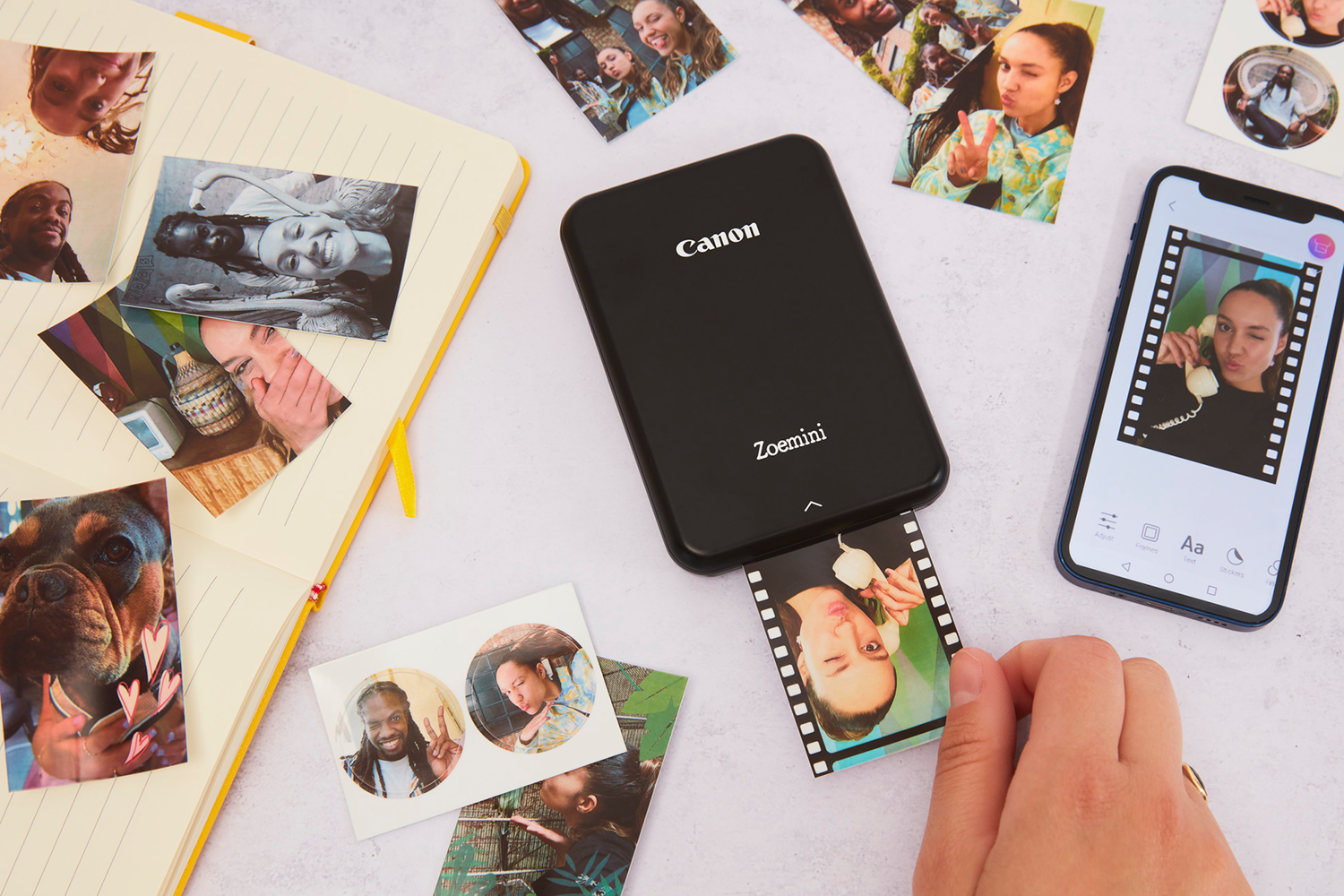 Een Canon Zoemini-printer die een foto afdrukt. Foto's eromheen, een telefoon die een bewerkte foto weergeeft.