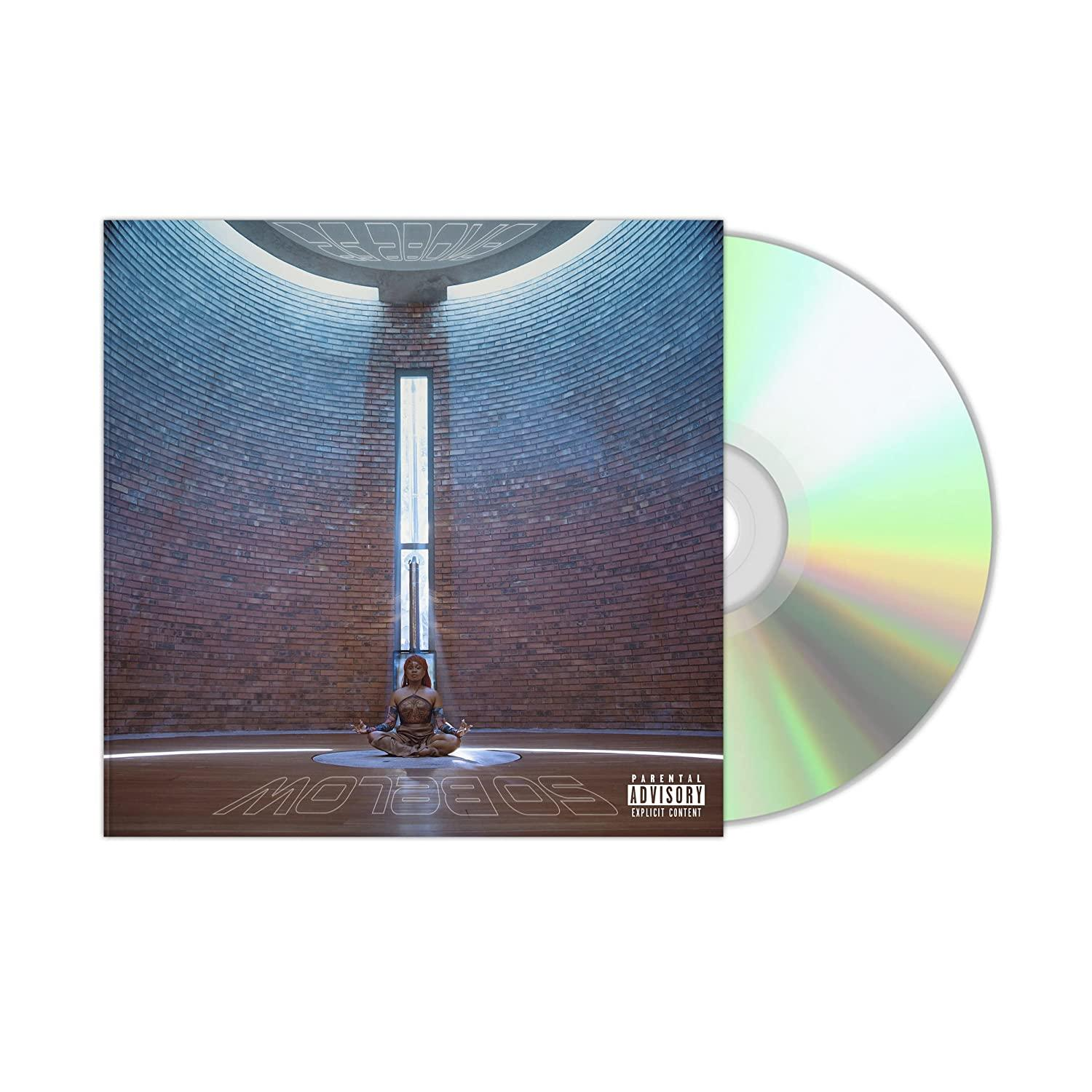 Boîtier de CD avec un CD à côté. L'œuvre montre une personne méditant dans un bâtiment en briques.