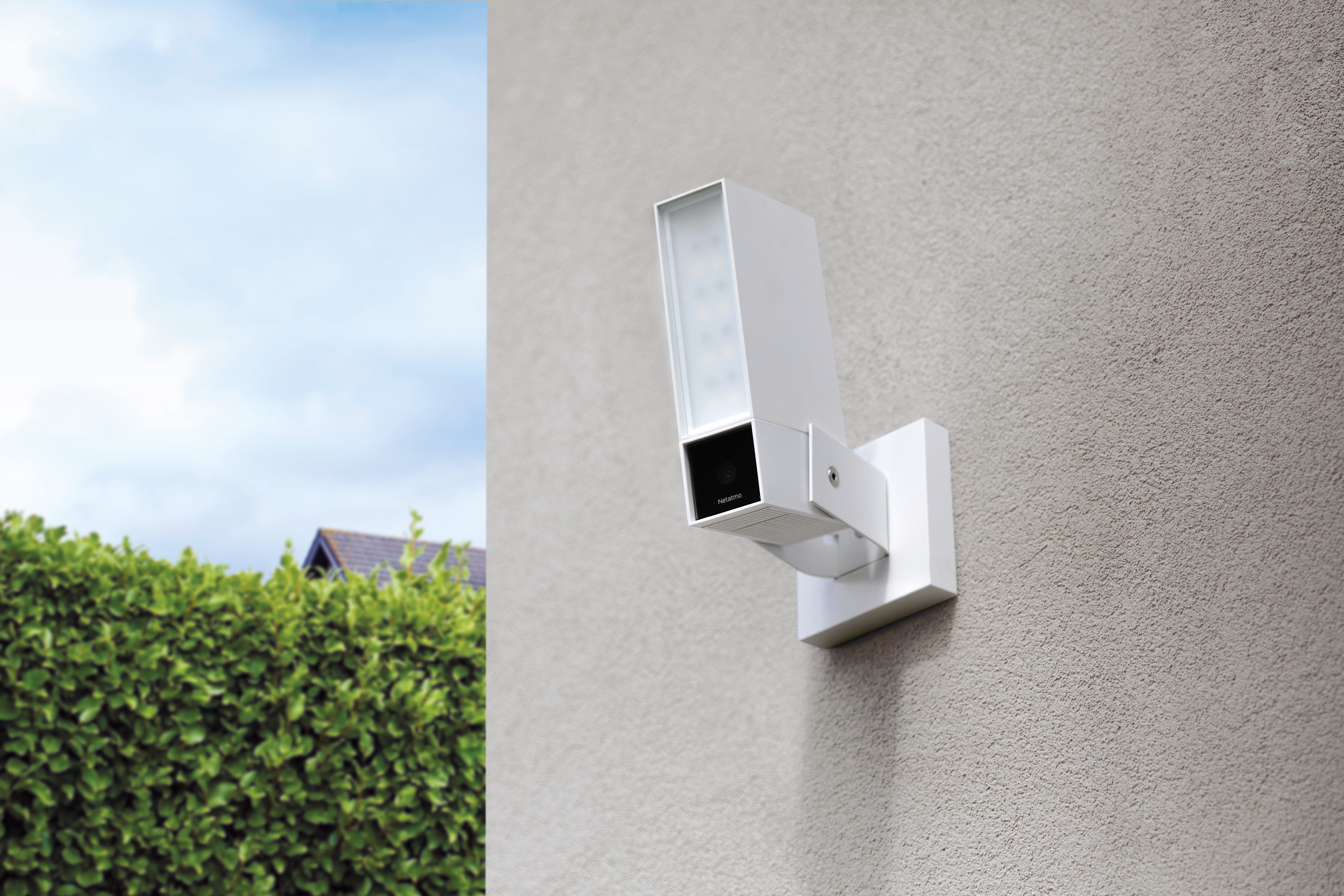 Une caméra de sécurité blanche montée sur un mur gris. Elle a une forme rectangulaire et un capteur noir.