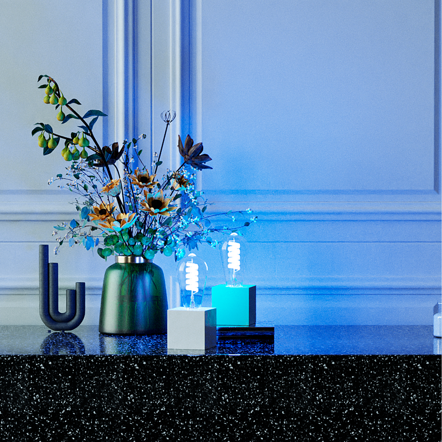 Flowers and lightbulbs on a table with a blue wall background.