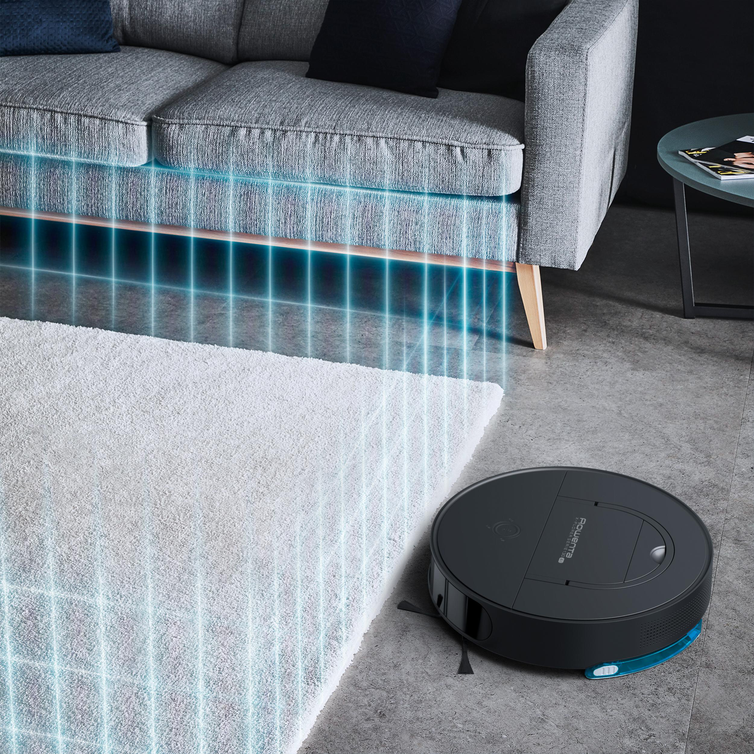 Roboterstaubsauger reinigt einen Raum. Ein weißer Teppich und ein graues Sofa sind sichtbar.