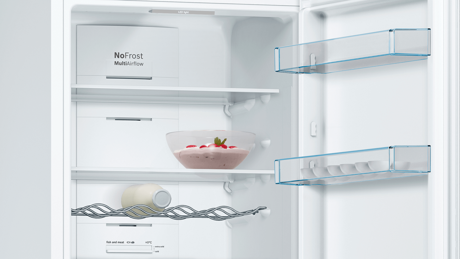 Vista interior de un refrigerador blanco con estantes, un cuenco con comida y una botella.