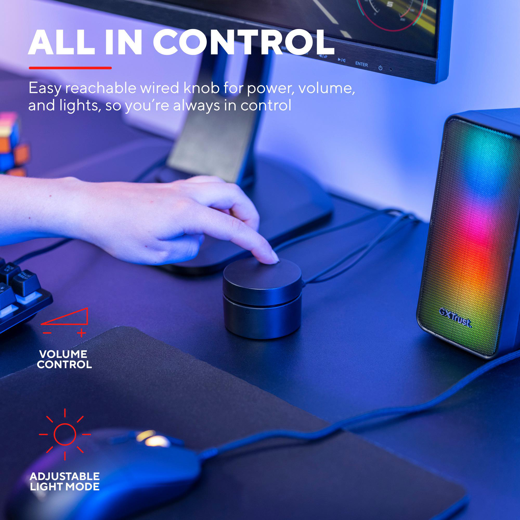Eine Hand berührt einen schwarzen Regler auf einem Schreibtisch mit Gaming-Lautsprecher und Maus.