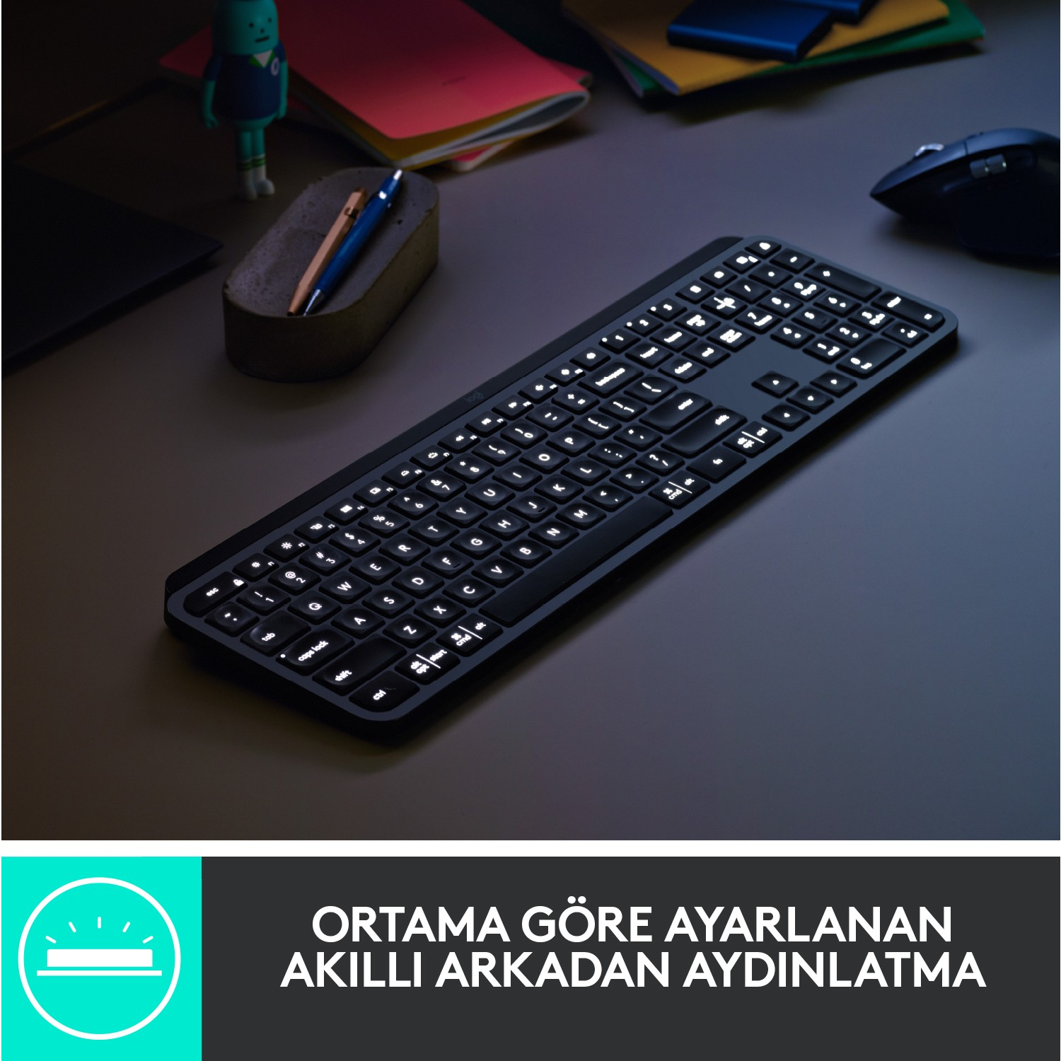 Aydınlatmalı tuşlara sahip siyah bir klavye, küçük yeşil bir figür ve bir kalemle bir masaya yerleştirilmiş.