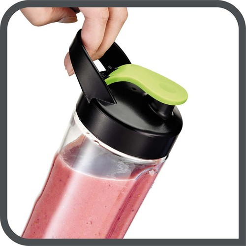 Yeşil bir tutacağı olan bir blender şişesini tutan bir el, pembe bir smoothie içeriyor.