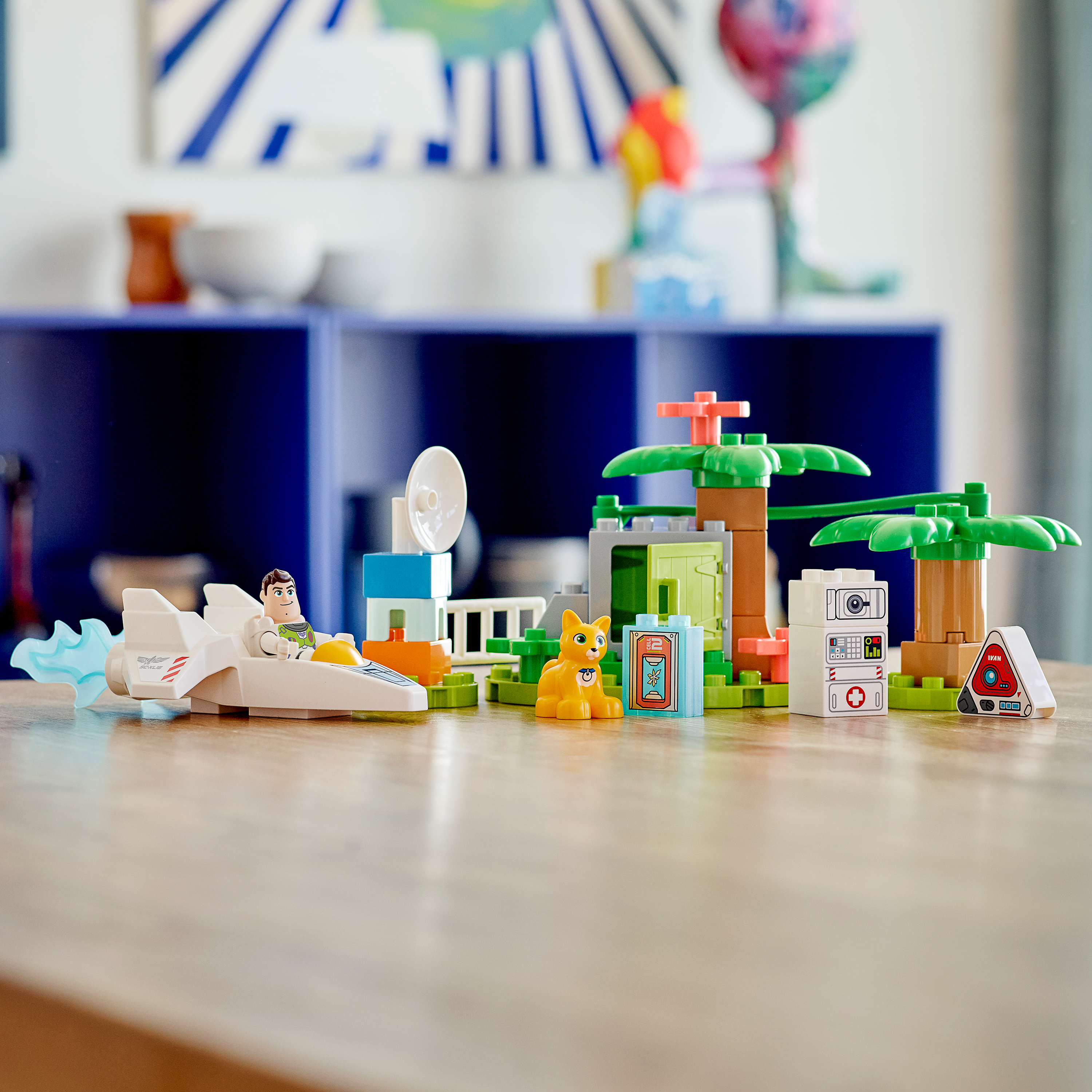 Ein LEGO DUPLO Set mit einer Rakete und einer Katze. Ein Holztisch und blauer Hintergrund. Bunt gefärbtes Spielzeug.