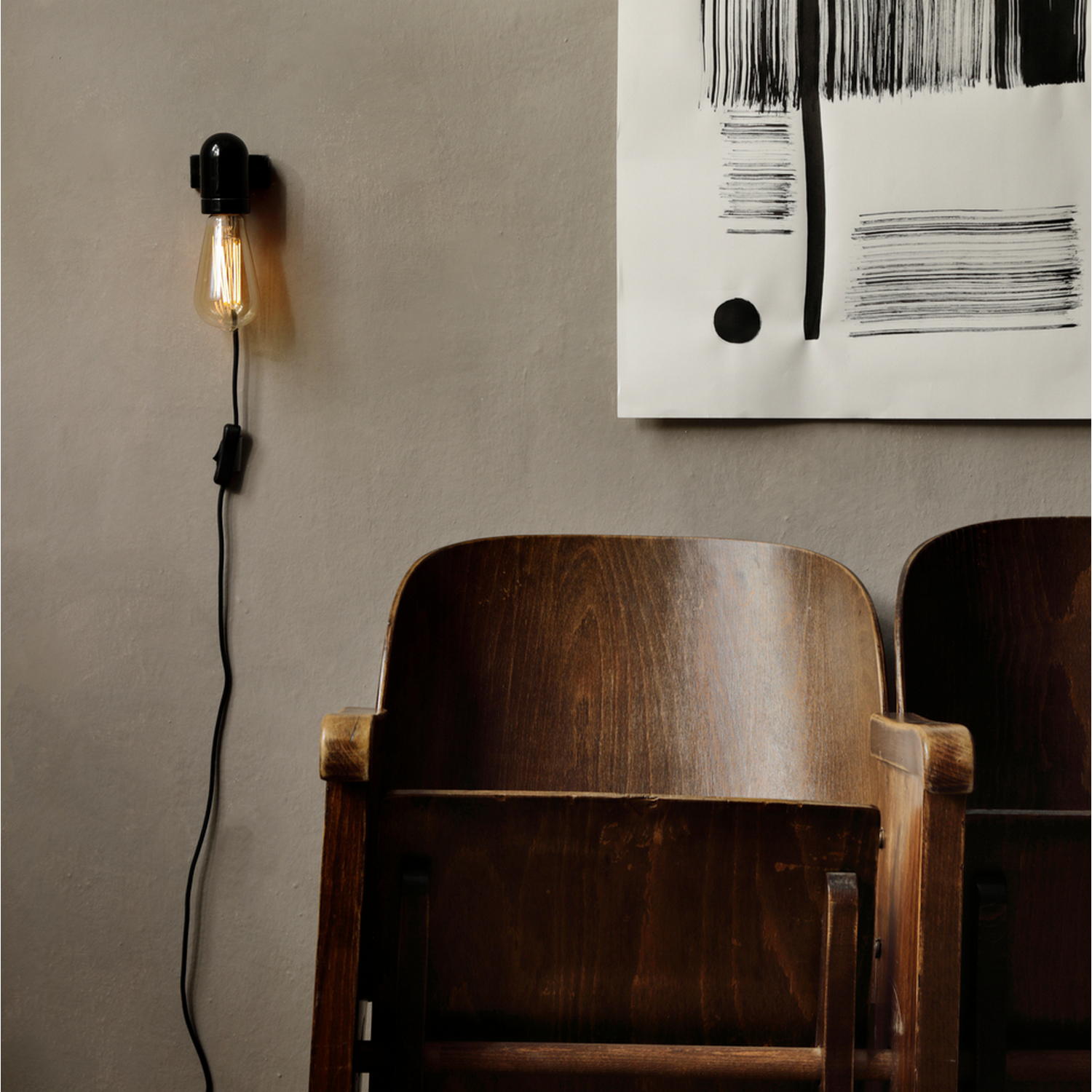 Wandlamp met een brandende gloeilamp en houten stoelen.