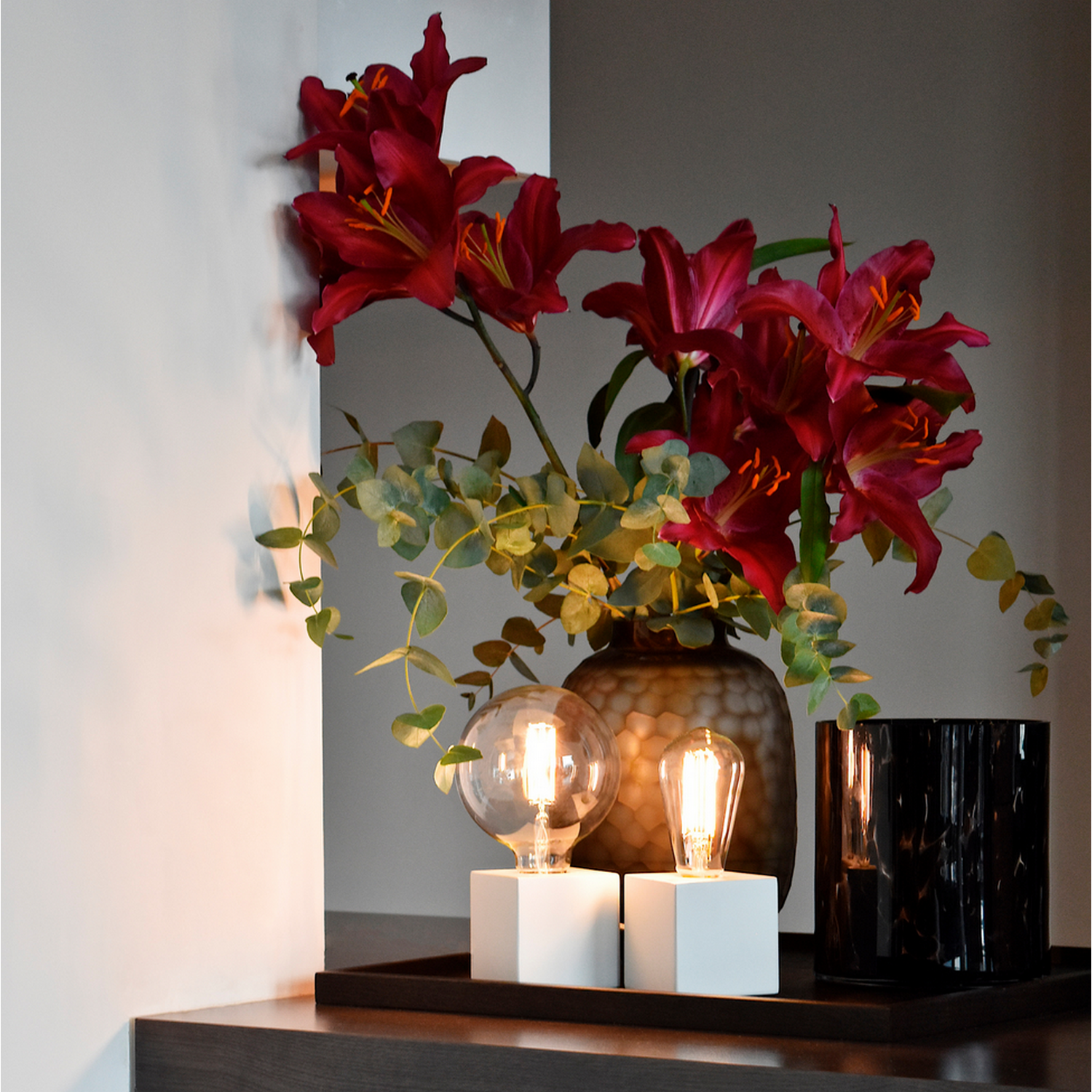 Afbeelding toont een modern interieur met rode bloemen, lichten en andere decoratieve items op een dienblad.
