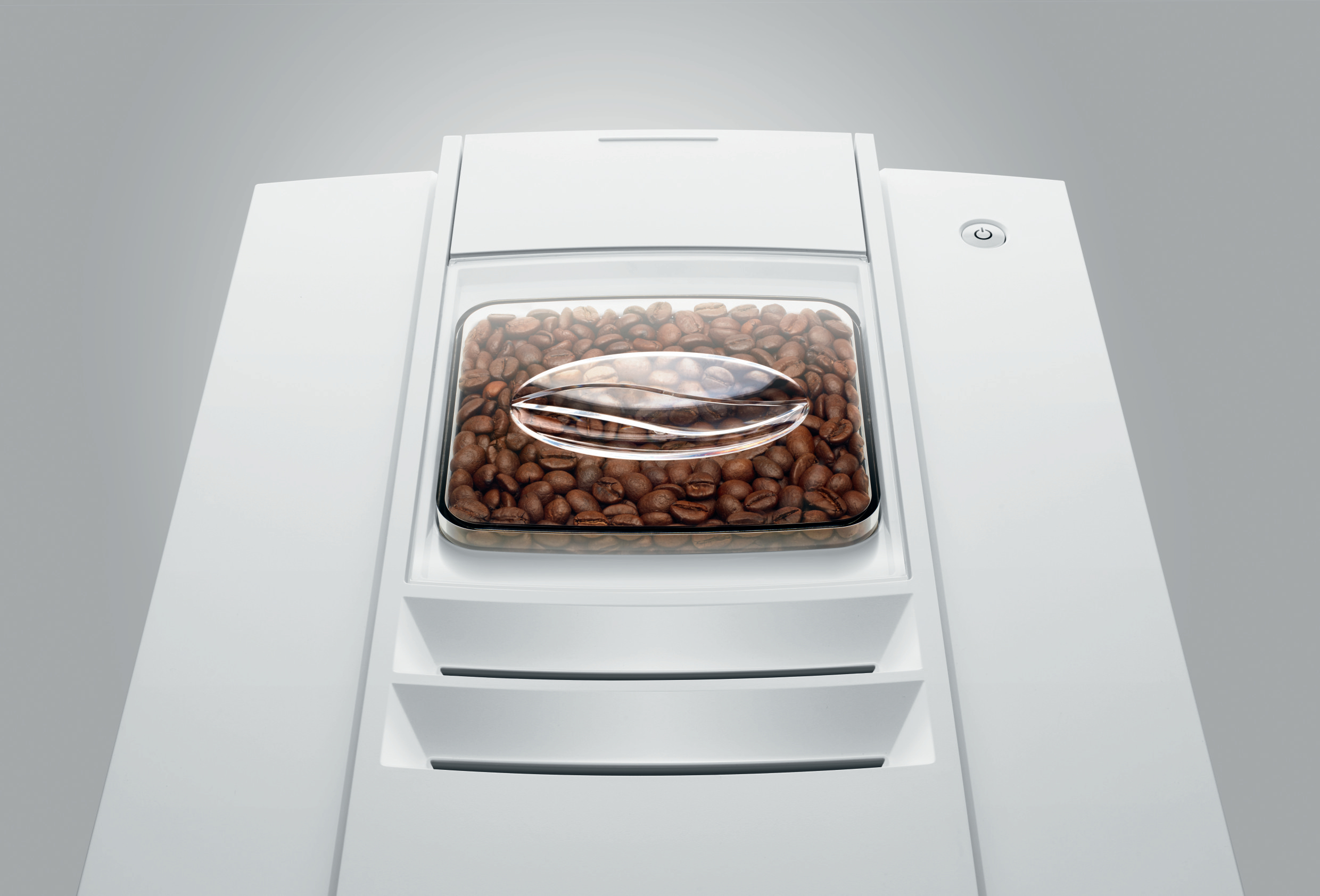Eine weiße Maschine mit Kaffeebohnen im Inneren. Die Maschine hat einen Glasbehälter mit Bohnen.