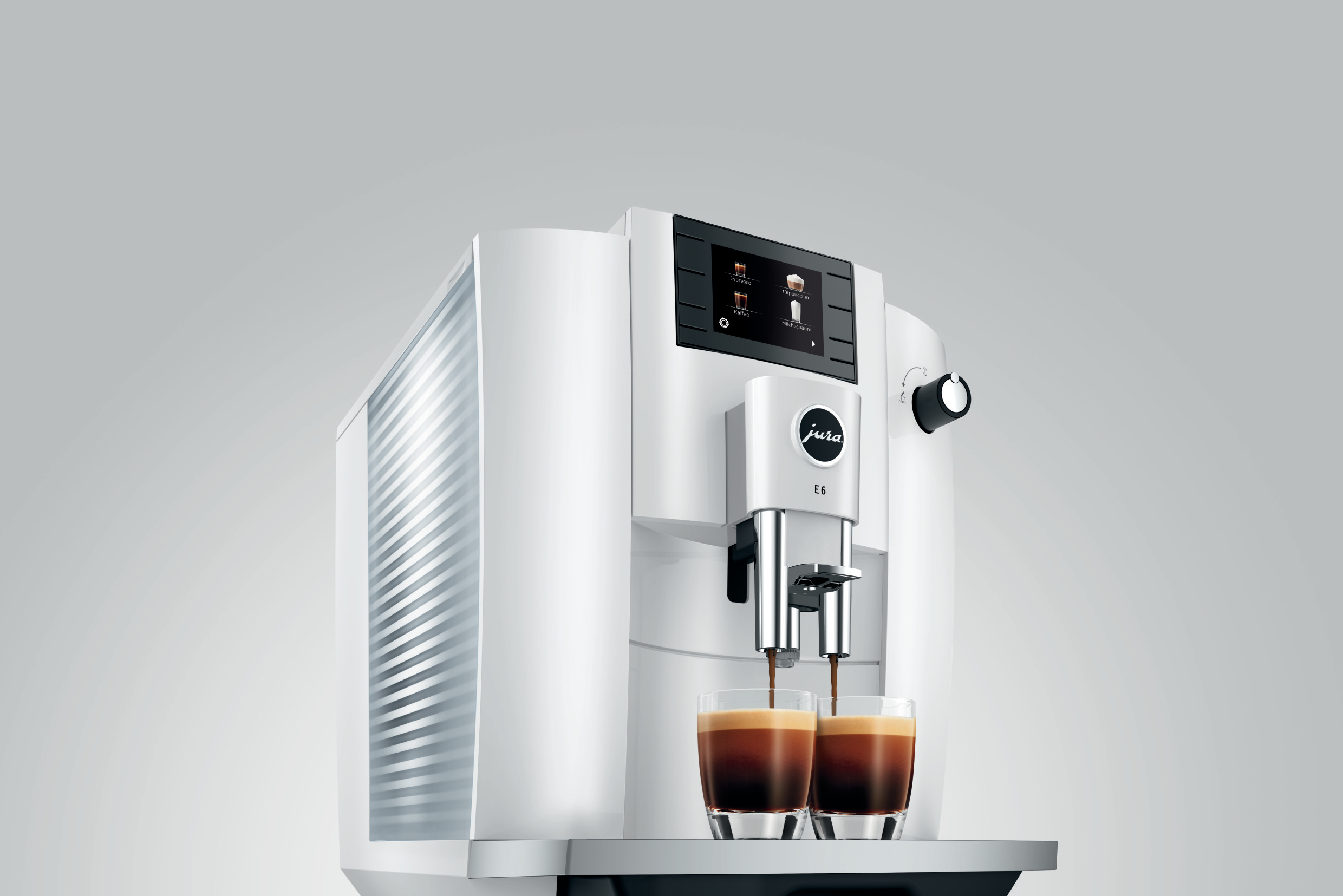 Eine weiße Jura E6 Kaffeemaschine wird gezeigt. Zwei Kaffeegläser werden gefüllt.