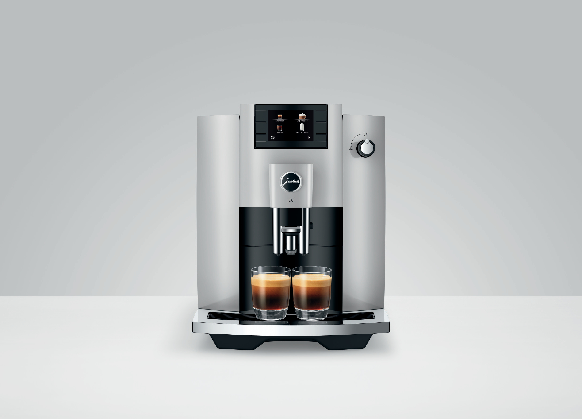 Silberne Kaffeemaschine mit zwei Kaffeegläsern auf einer weißen Oberfläche.