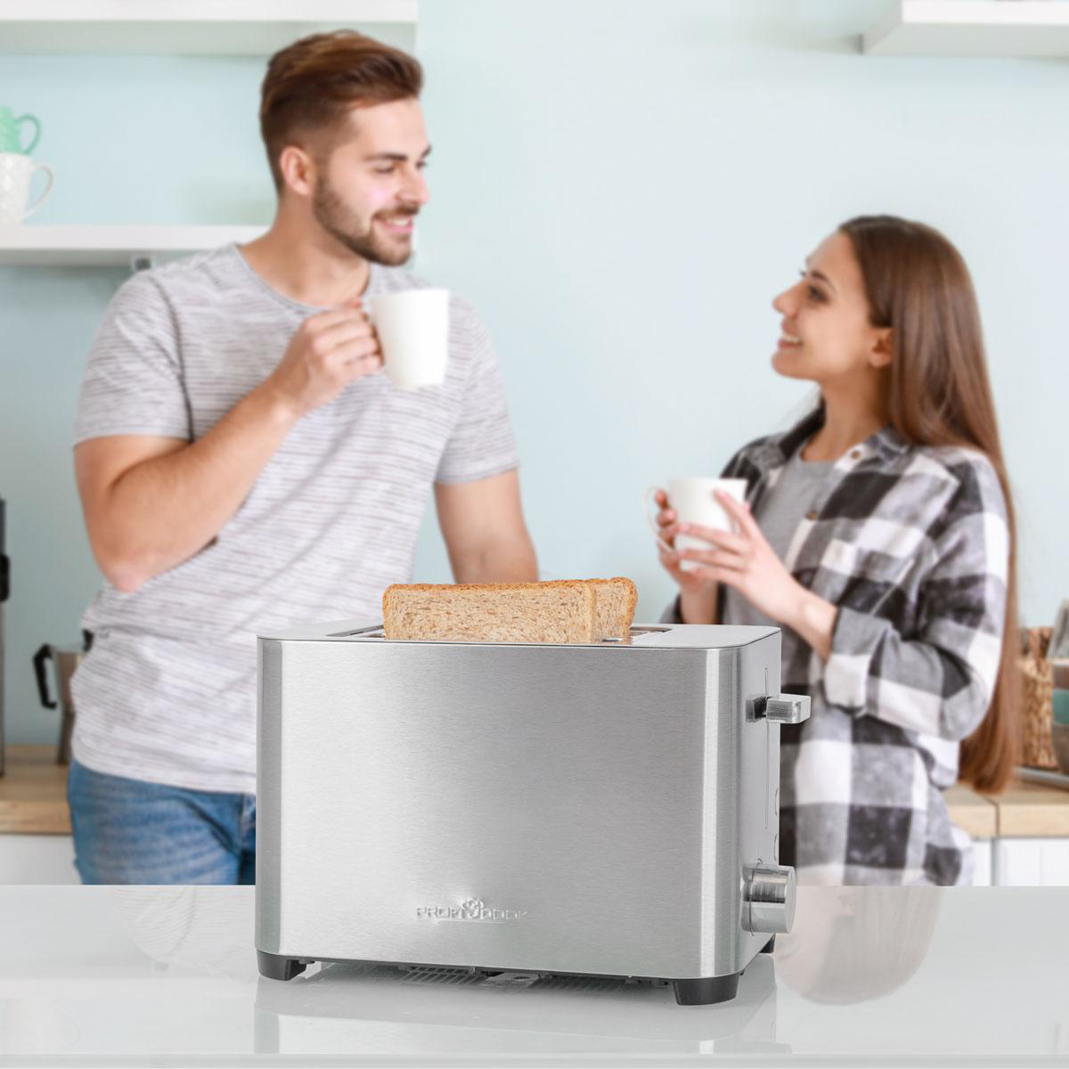 Ein Mann und eine Frau trinken Kaffee, während Toast in einem Toaster ist.