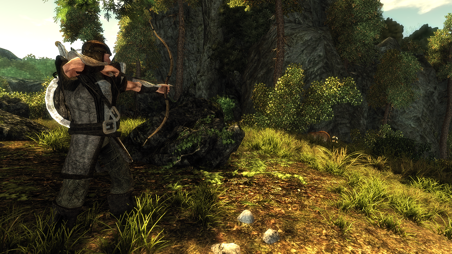 Man with bow and arrow, aiming at something in a forest. Green foliage and rocky terrain.