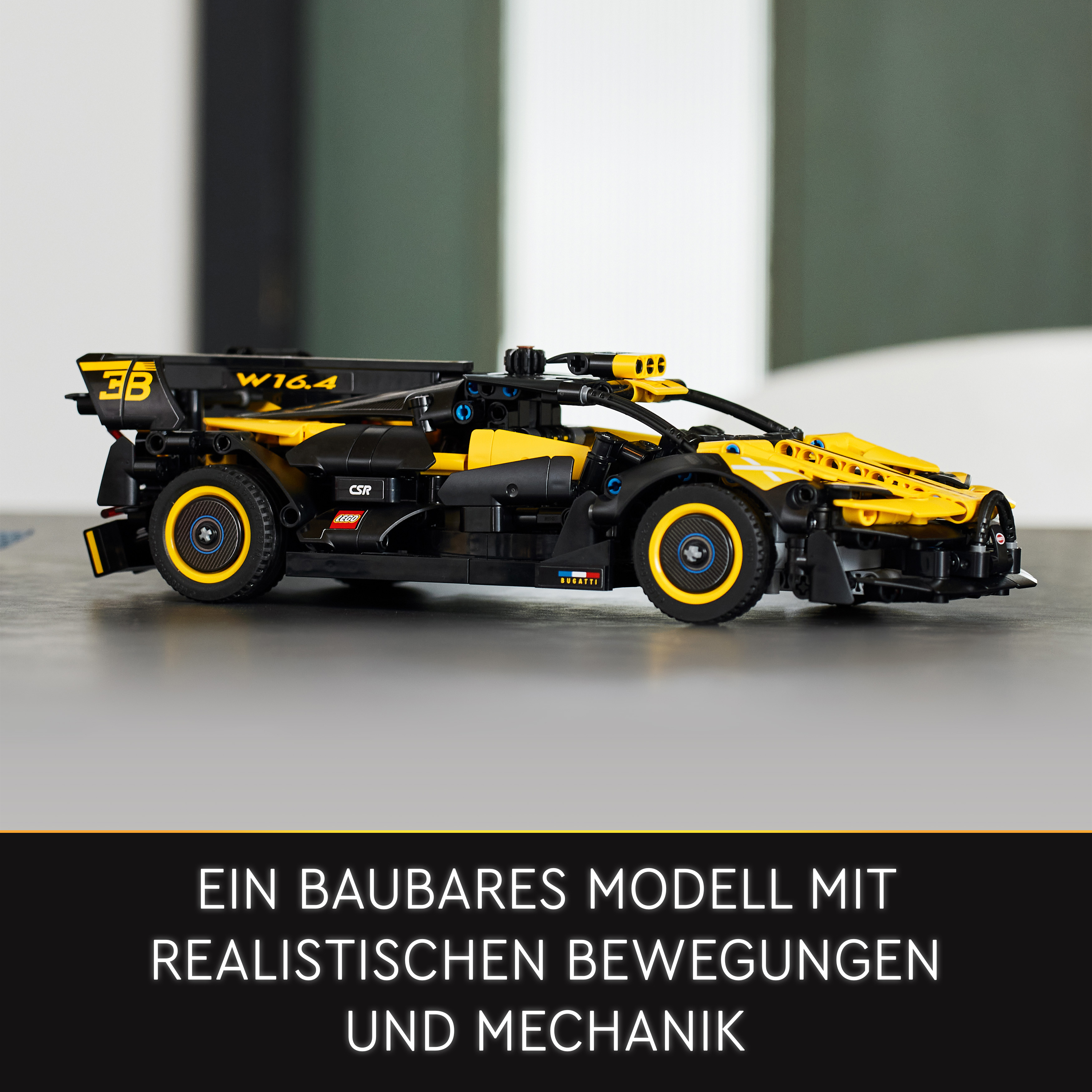 Ein gelb-schwarzes Lego-Rennauto auf grauer Oberfläche. Text: Ein Baubares Modell...